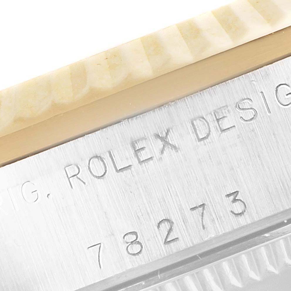 This image focuses on the side of a Rolex Mid-Size 78273 Women
s Steel and Gold (two tone) White Dial 78273 Women
s Steel and Gold (two tone) White Dial watch, showing part of the bezel and engraved case with the model number 78273.