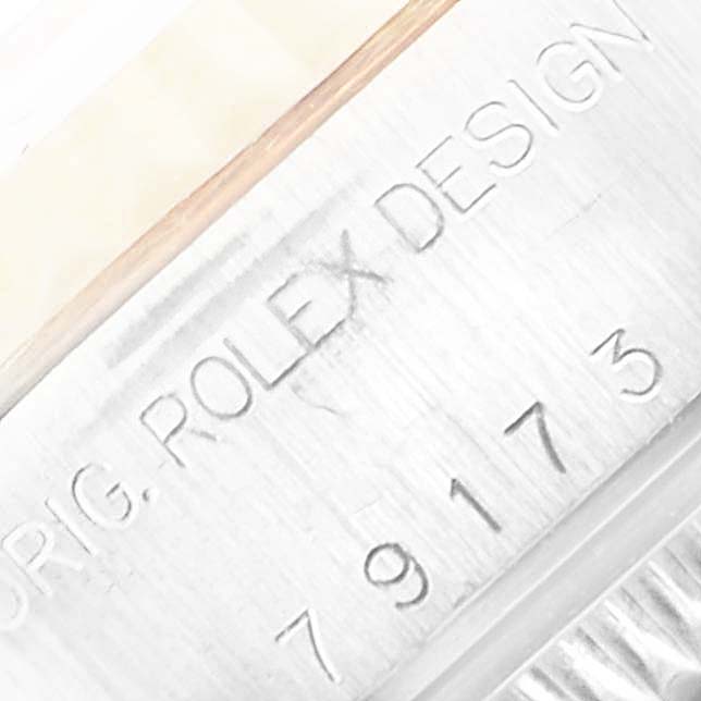 The image shows an angled close-up of a Rolex Datejust 79173 Women's Steel and Gold (two tone) Blue Dial 79173 Women's Steel and Gold (two tone) Blue Dial watch, focusing on the engraved "ROLEX DESIGN" text and model number.