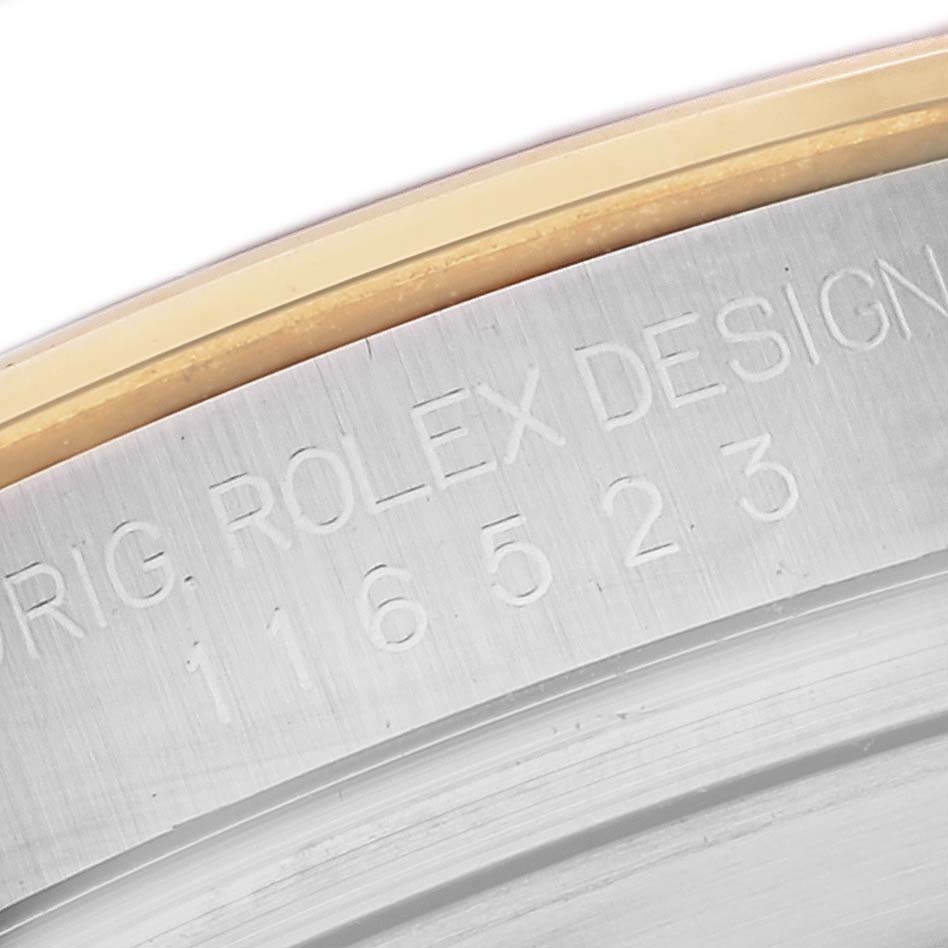 This image shows a close-up of the engraved serial number and "ROLEX DESIGN" text on the case of a Rolex Daytona 116523 Men's Steel and Gold (two tone) Black Dial 116523 Men's Steel and Gold (two tone) Black Dial watch.