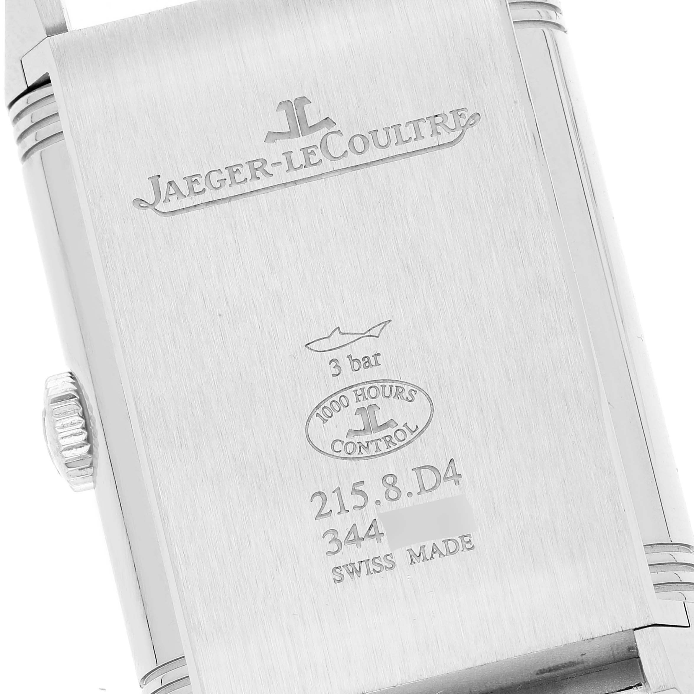 The image shows the back case of a Jaeger-LeCoultre Reverso watch, featuring engravings and the crown on the side.