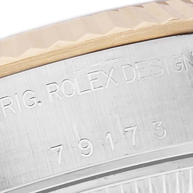 This is a close-up view of the side and bezel of a Rolex Datejust 79173 Women's Steel and Gold (two tone) Champagne Dial 79173 Women's Steel and Gold (two tone) Champagne Dial watch, showing part of its engraved text and fluted bezel.