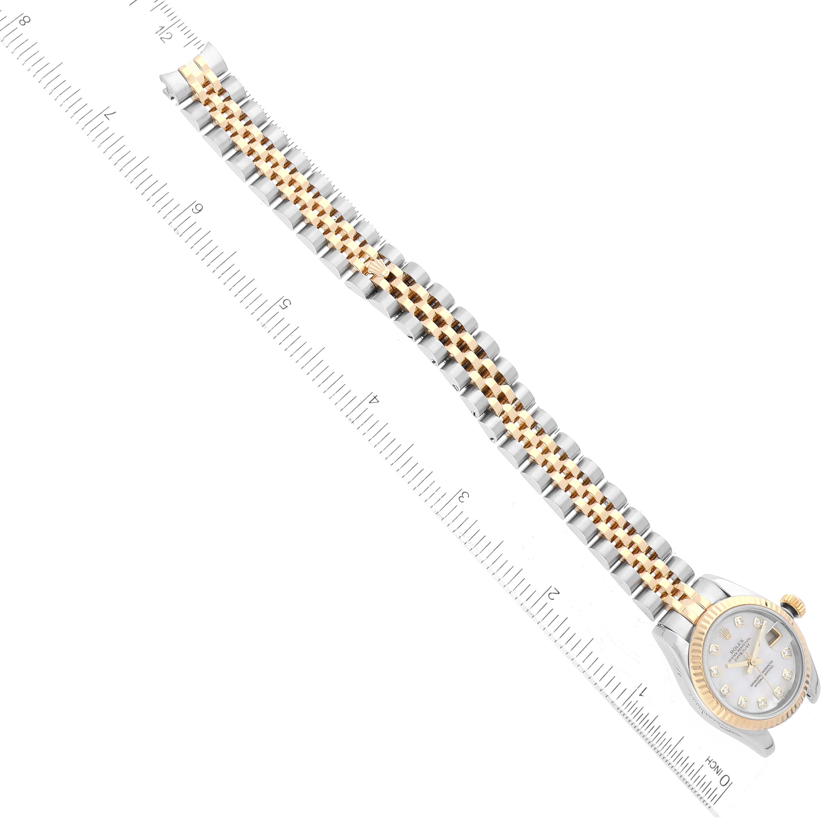 This image shows a Rolex Datejust 179173 Women's Steel and Gold (two tone) Mother of Pearl Dial 179173 Women's Steel and Gold (two tone) Mother of Pearl Dial watch laid flat, with a focus on the face and bracelet, alongside a ruler for scale.