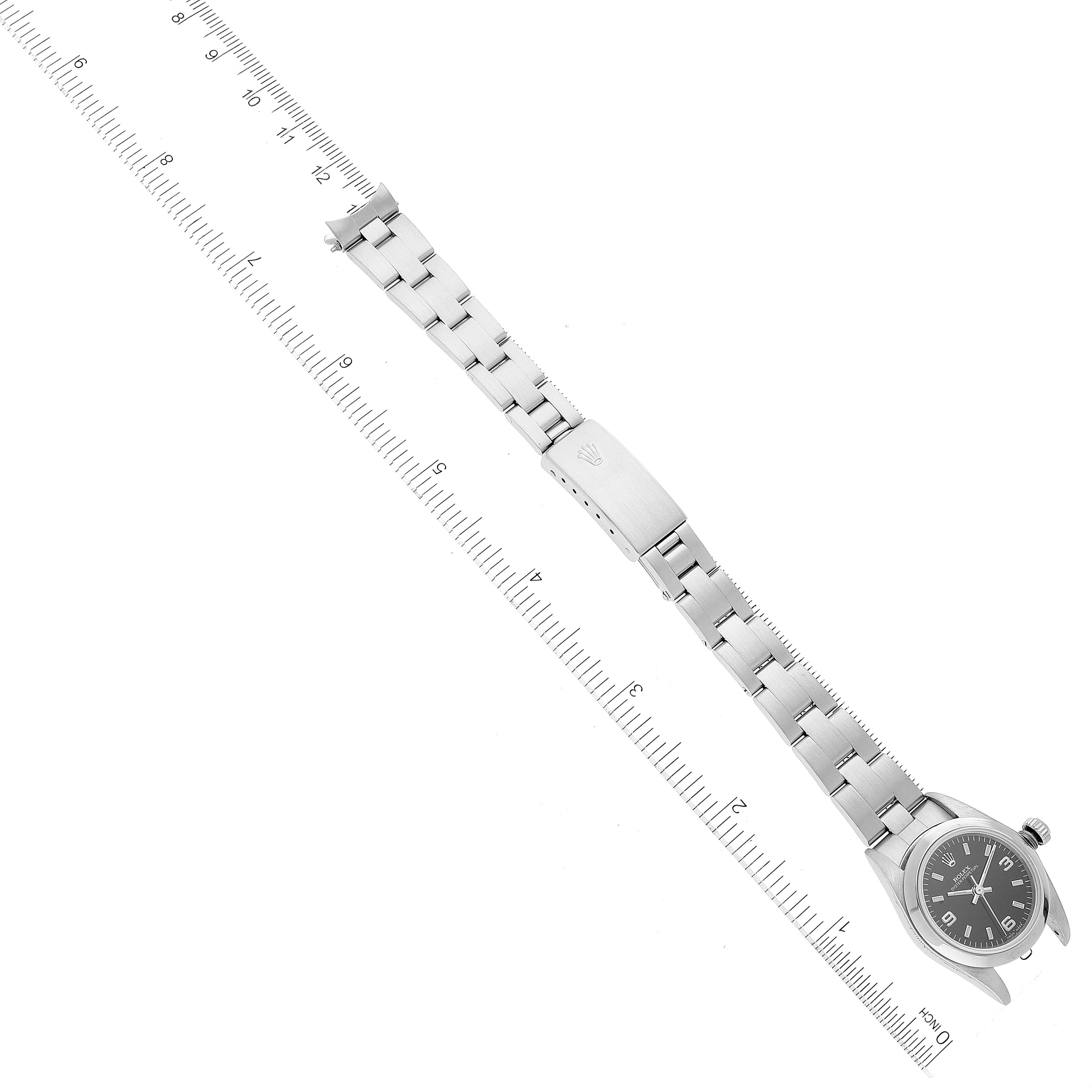 The image shows a Rolex Oyster Perpetual 76080 Women's Stainless Steel Black Dial 76080 Women's Stainless Steel Black Dial watch laid flat with its metallic band extended and measured against a ruler.