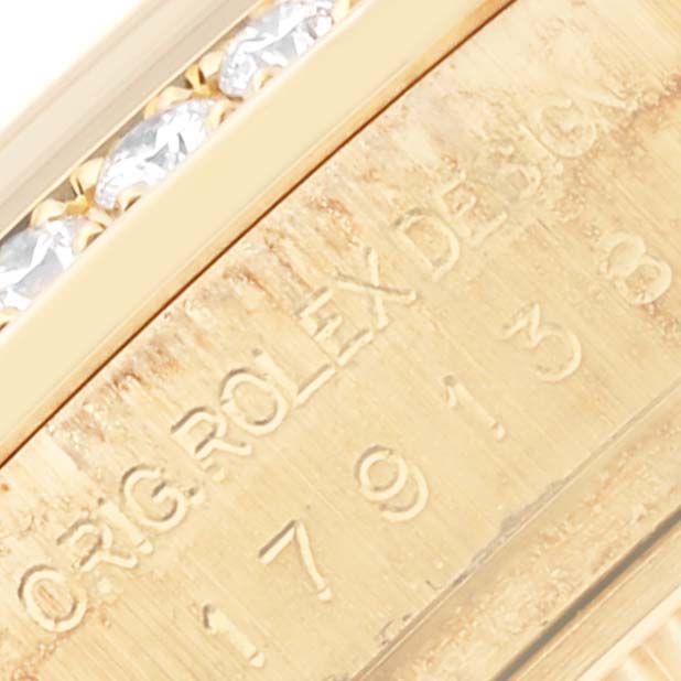 The image shows a close-up of the Rolex President 179138 Women's Yellow Gold Champagne Dial 179138 Women's Yellow Gold Champagne Dial watch's interior engraving and diamond details on the bezel.