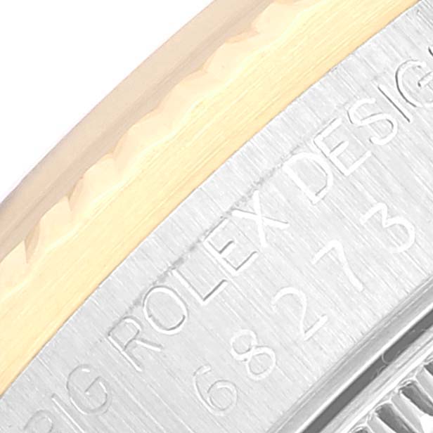 The image shows a close-up of the side and edge of a Rolex Mid-Size 68273 Women
s Steel and Gold (two tone) Black Dial 68273 Women
s Steel and Gold (two tone) Black Dial watch, highlighting the engraved serial number and design text.