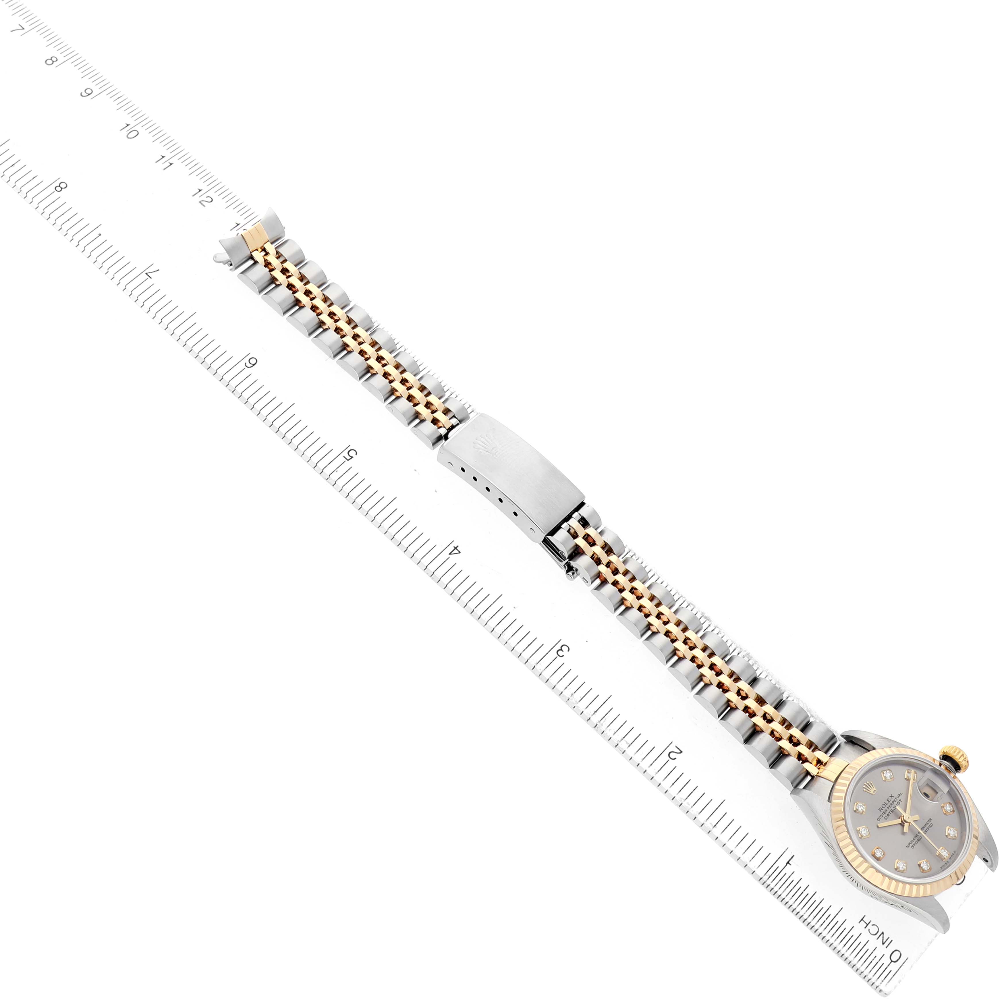 The image shows a Rolex Datejust 79173 Women's Steel and Gold (two tone) Silver Dial watch at an angled view, highlighting its face, bezel, and jubilee bracelet alongside a ruler.