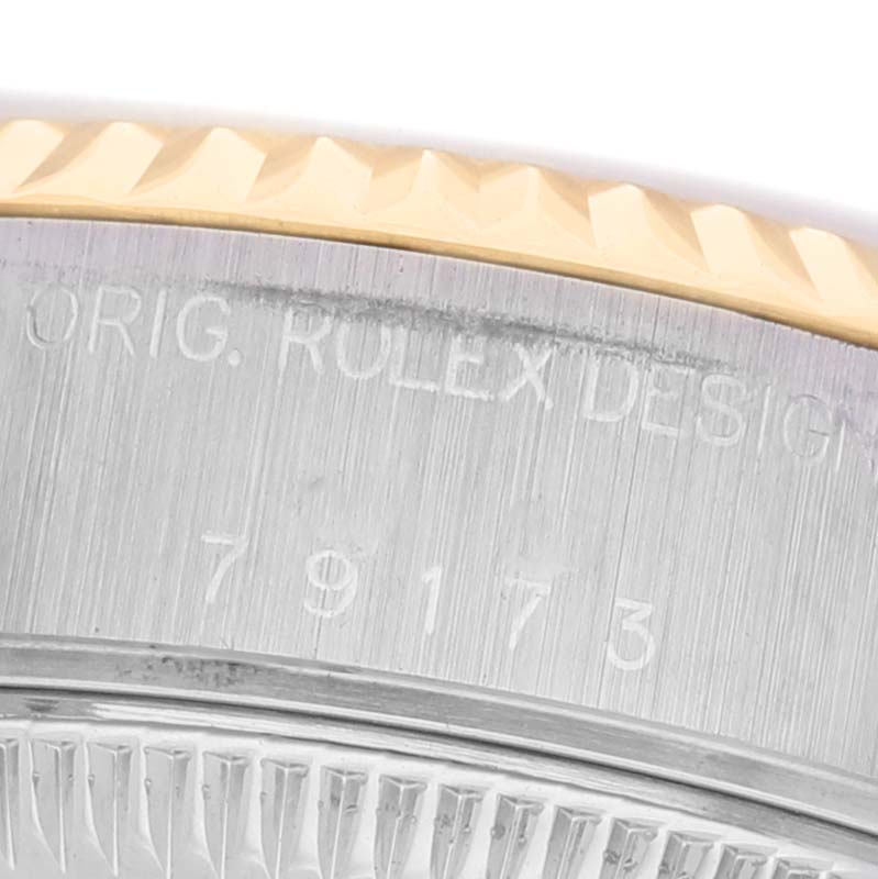 The image shows a close-up of the bezel and engraved serial number on a Rolex Datejust 79173 Women's Steel and Gold (two tone) Silver Dial watch.