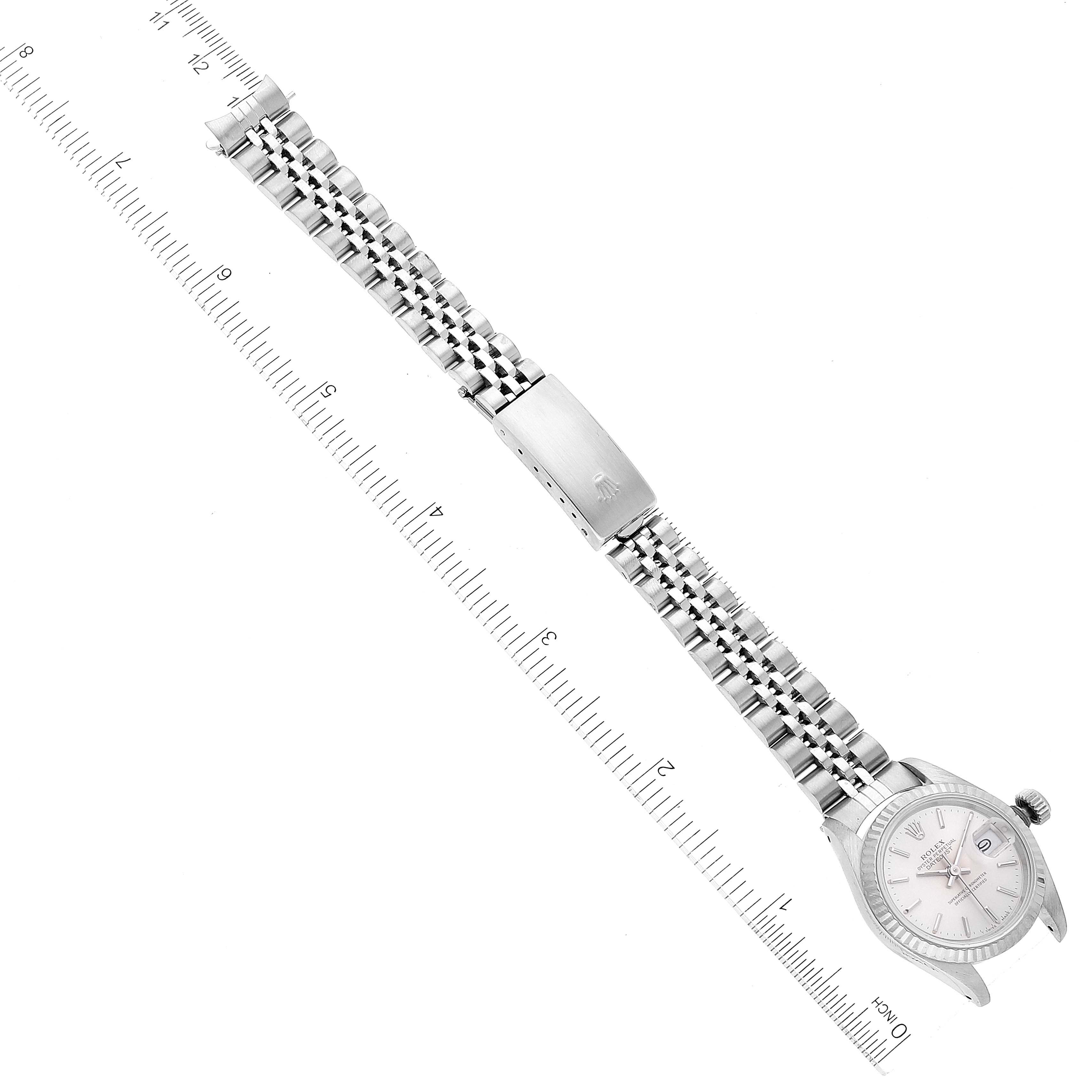 The Rolex Datejust 69174 Women's Stainless Steel Silver Dial 69174 Women's Stainless Steel Silver Dial watch is shown laid flat with its bracelet extended and aligned next to a ruler for scale.