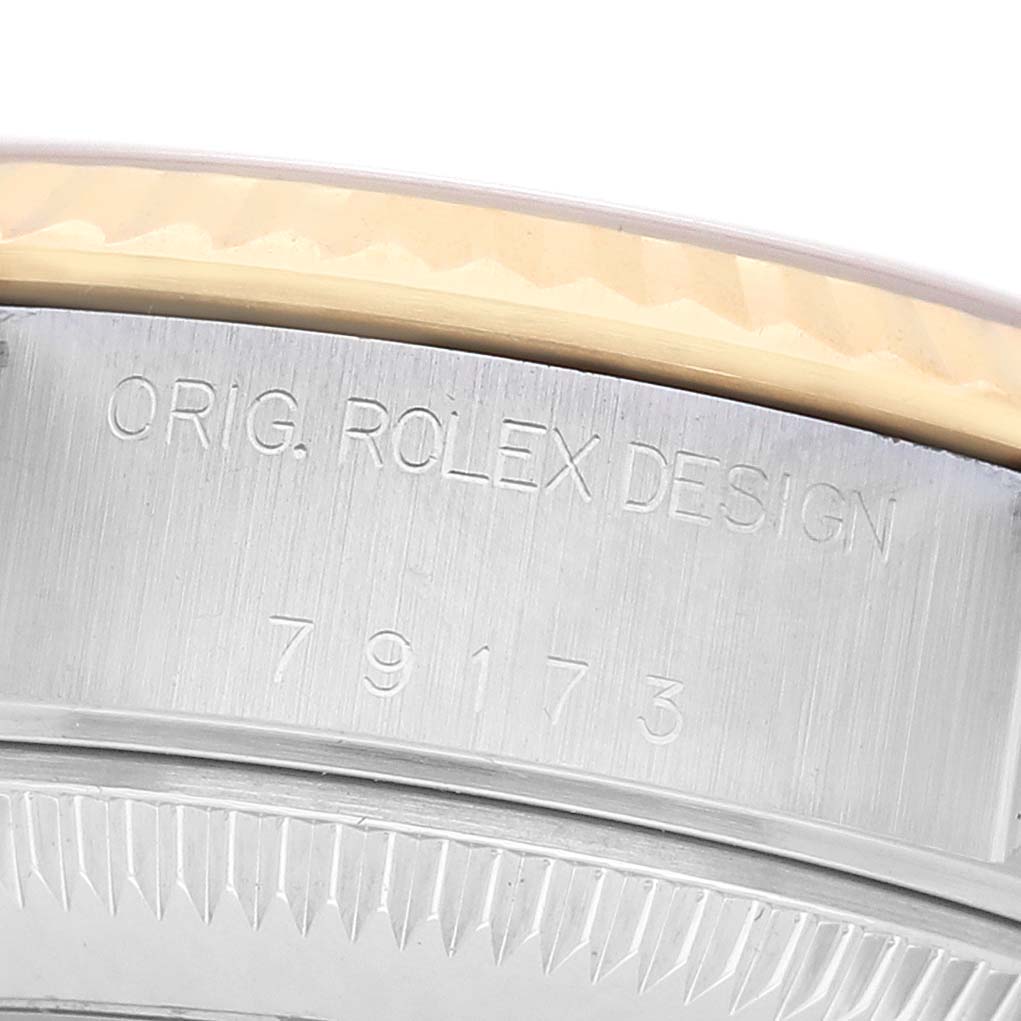 The image shows a close-up of the engraving on the side of the case and bezel of a Rolex Datejust 79173 Women's Steel and Gold (two tone) Champagne Dial watch.