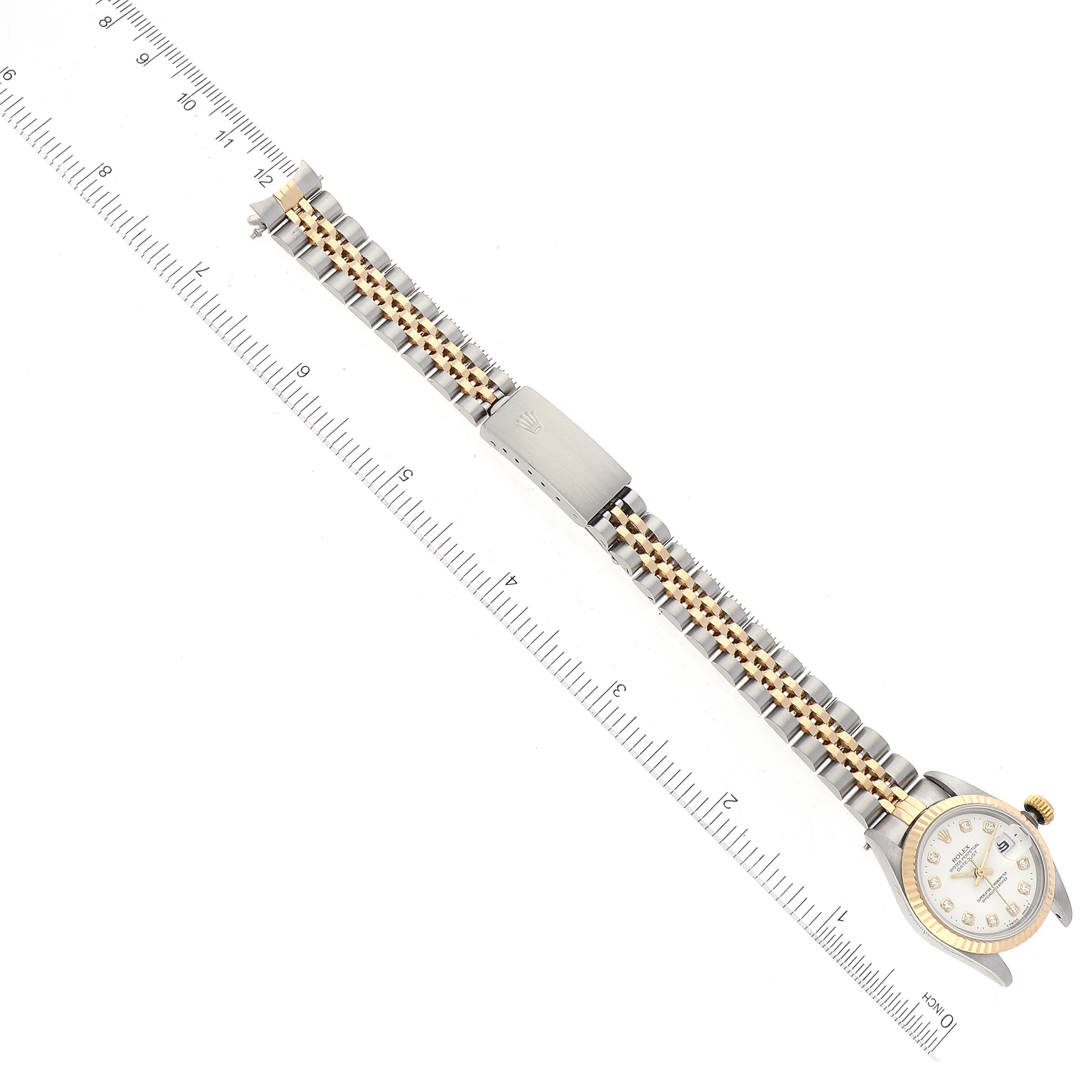 The Rolex Datejust 69173 Women's Steel and Gold (two tone) White Dial 69173 Women's Steel and Gold (two tone) White Dial watch is shown lying flat, displaying the face, bracelet, and clasp next to a ruler for scale.