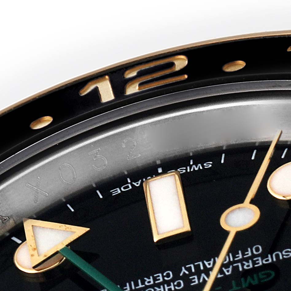 This close-up image shows the bezel and part of the dial with hour markers of a Rolex GMT-Master 116713 Men's Steel and Gold (two tone) Black Dial 116713 Men's Steel and Gold (two tone) Black Dial watch.