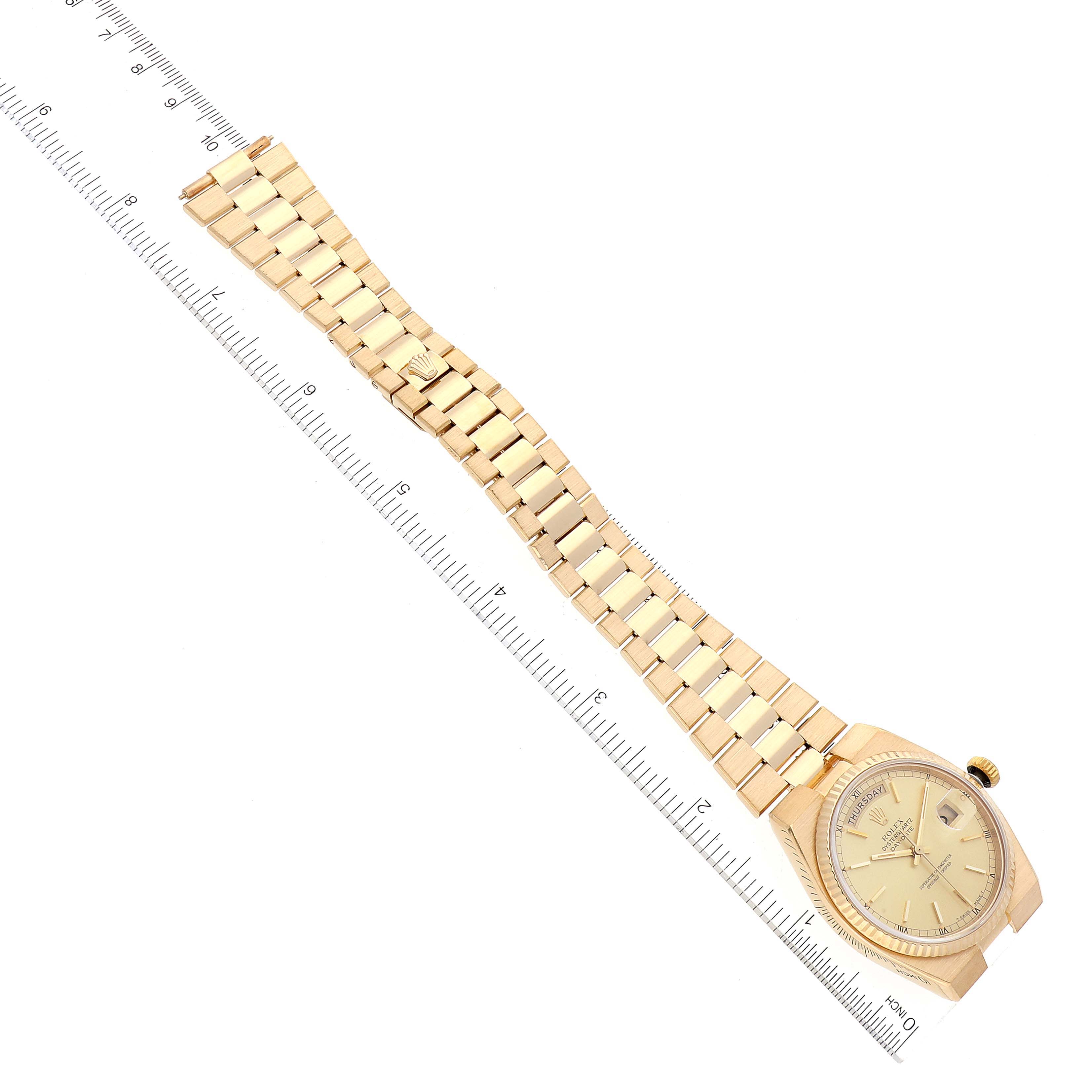 The image shows a Rolex President 19018 Men
s Yellow Gold Champagne Dial 19018 Men
s Yellow Gold Champagne Dial model watch laid flat with its gold bracelet fully extended alongside a ruler for measurement.