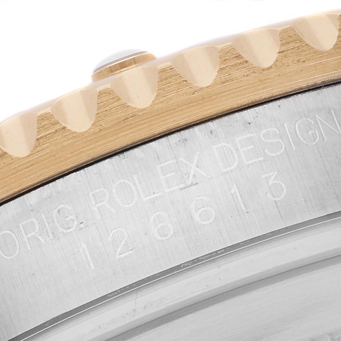 The image shows a close-up of the edge of the bezel and case side of a Rolex Submariner 126613LB Men
s Steel and Gold (two tone) Blue Dial 126613LB Men
s Steel and Gold (two tone) Blue Dial, displaying part of its design inscription and model number.
