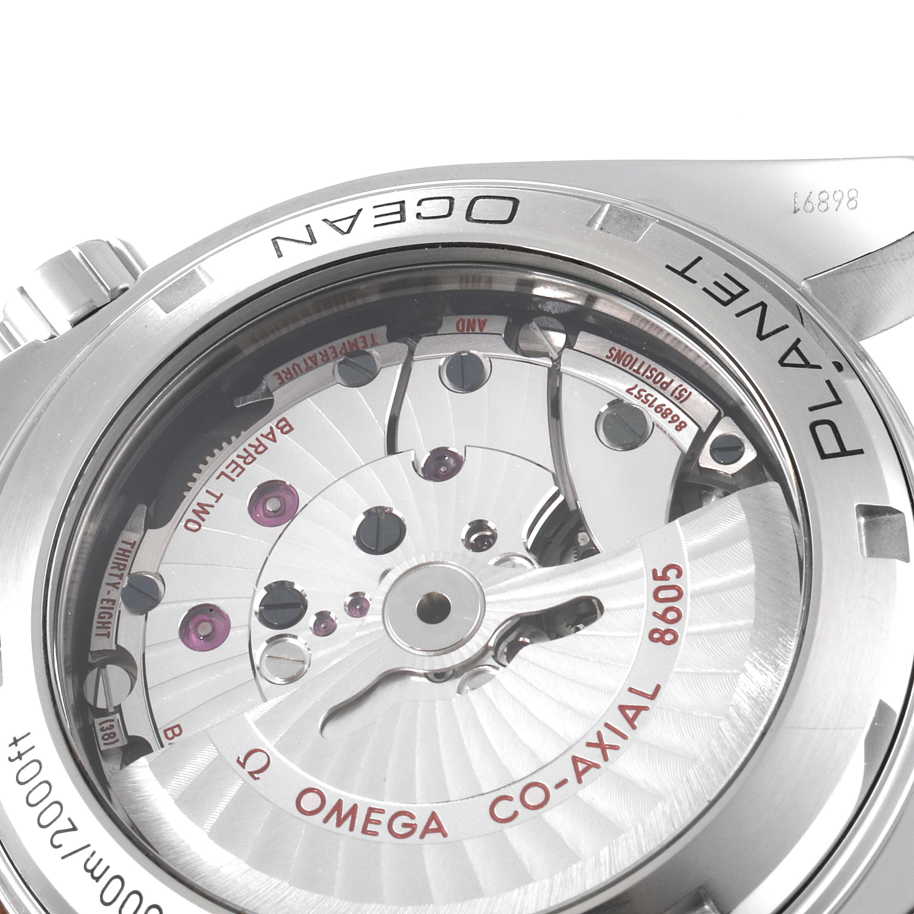 The image shows a close-up of the Omega Planet Ocean 232.30.44.22.01.001 Men's Stainless Steel Black Dial 232.30.44.22.01.001 Men's Stainless Steel Black Dial model's case back, revealing the Co-Axial 8605 movement and internal components.