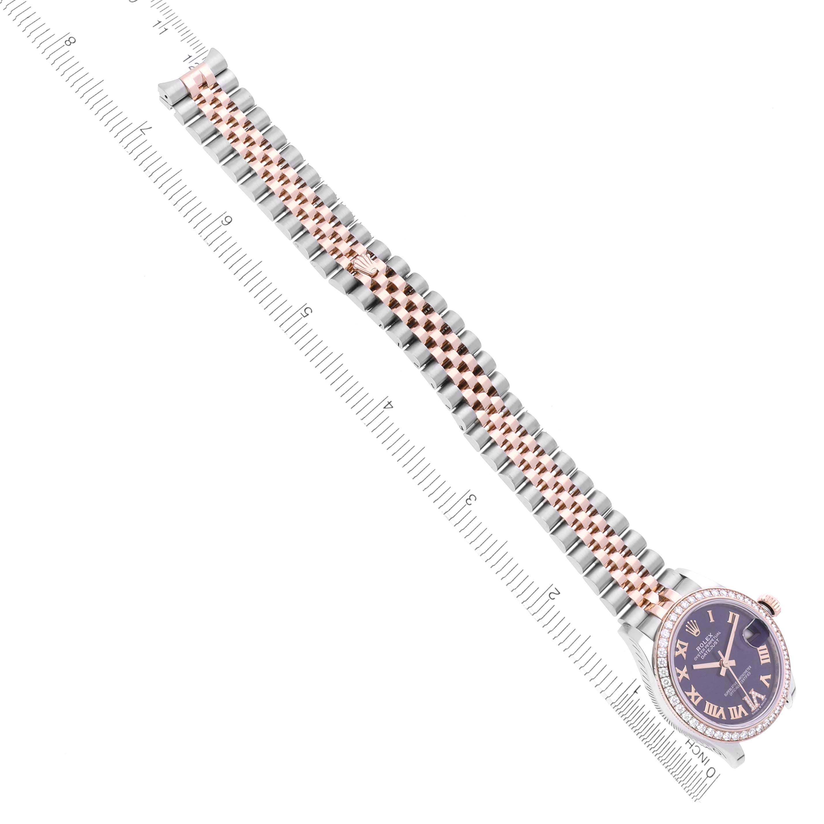 The Rolex Mid-Size 278381RBR-0020 Women's Steel and Gold (two tone) Purple Dial watch is shown from above, highlighting the bracelet and watch face aligned with a ruler.