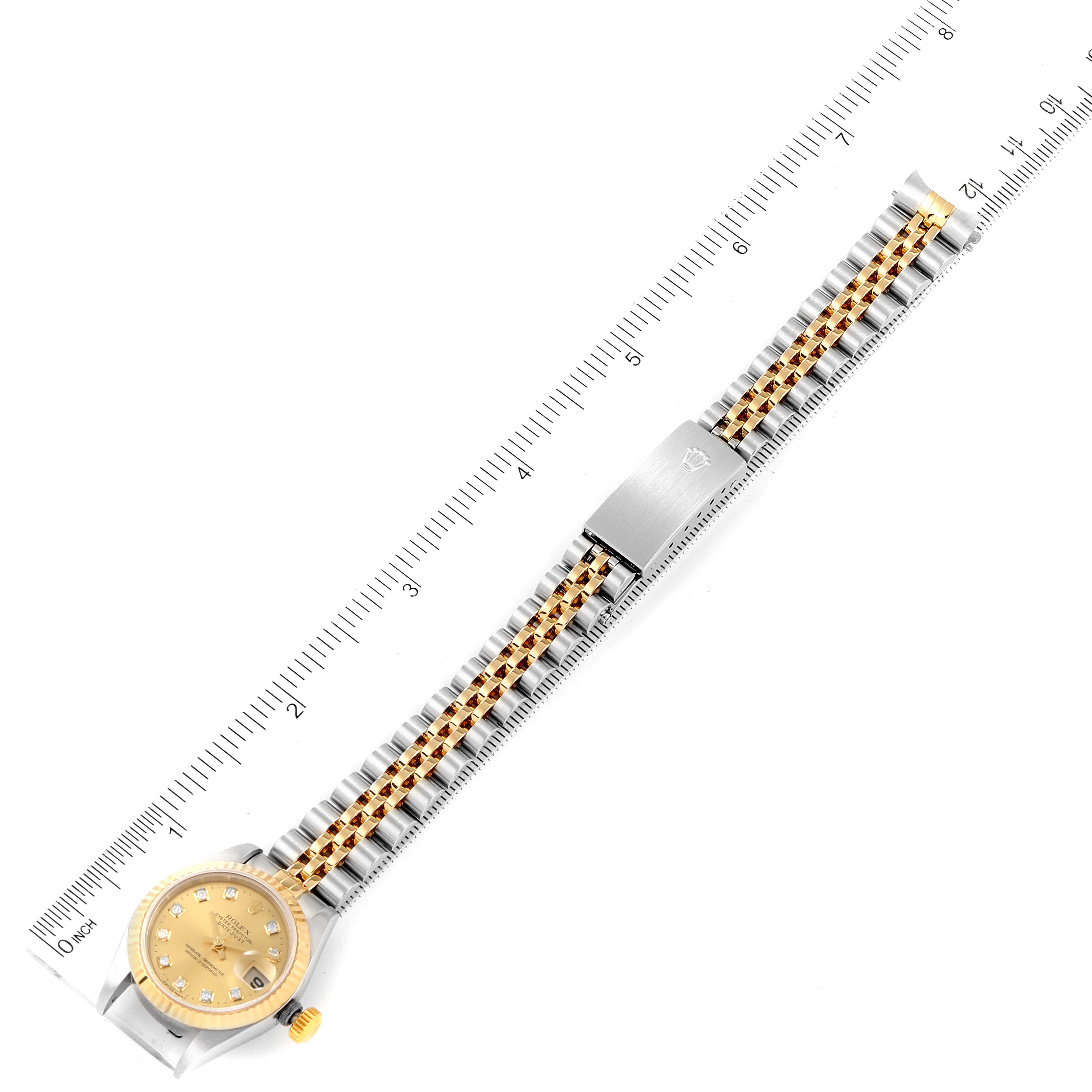 This image shows an overhead view of a Rolex Datejust 79173 Women
s Steel and Gold (two tone) Champagne Dial 79173 Women
s Steel and Gold (two tone) Champagne Dial watch, featuring its face, bracelet, and clasp next to a ruler.