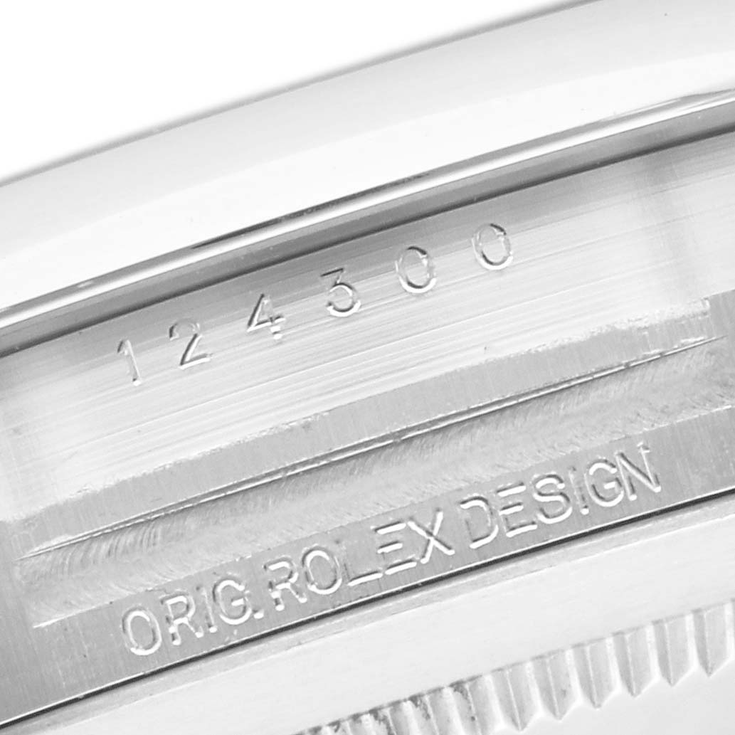 The image shows a close-up of the side of a Rolex Oyster Perpetual 124300 Men's Stainless Steel Silver Dial 124300 Men's Stainless Steel Silver Dial watch, highlighting the engraved model number and "ORIG. ROLEX DESIGN."