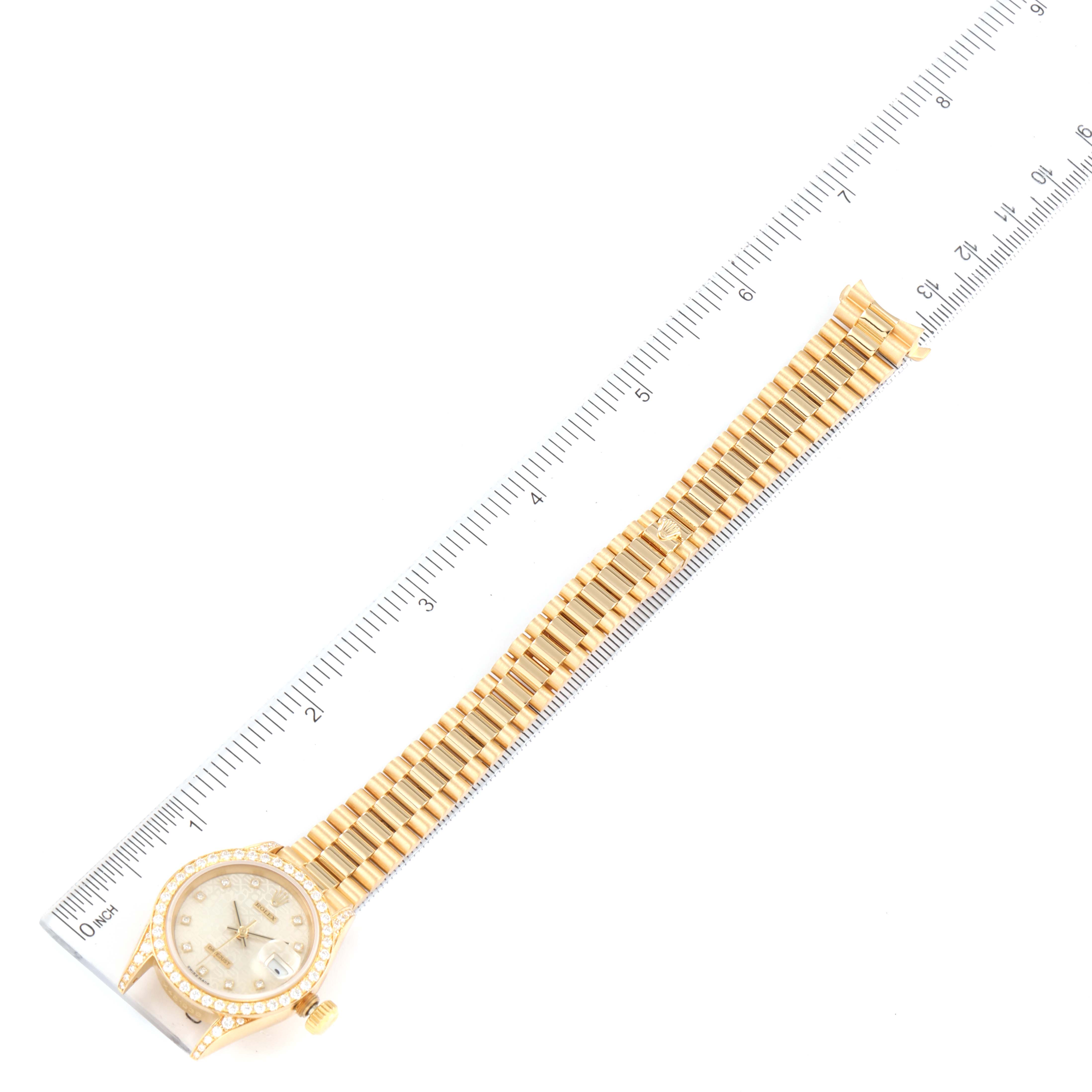 The image shows a top view of a Rolex President 69158 Women's Yellow Gold Silver Dial 69158 Women's Yellow Gold Silver Dial model watch, highlighting its full bracelet and dial, placed next to a ruler.