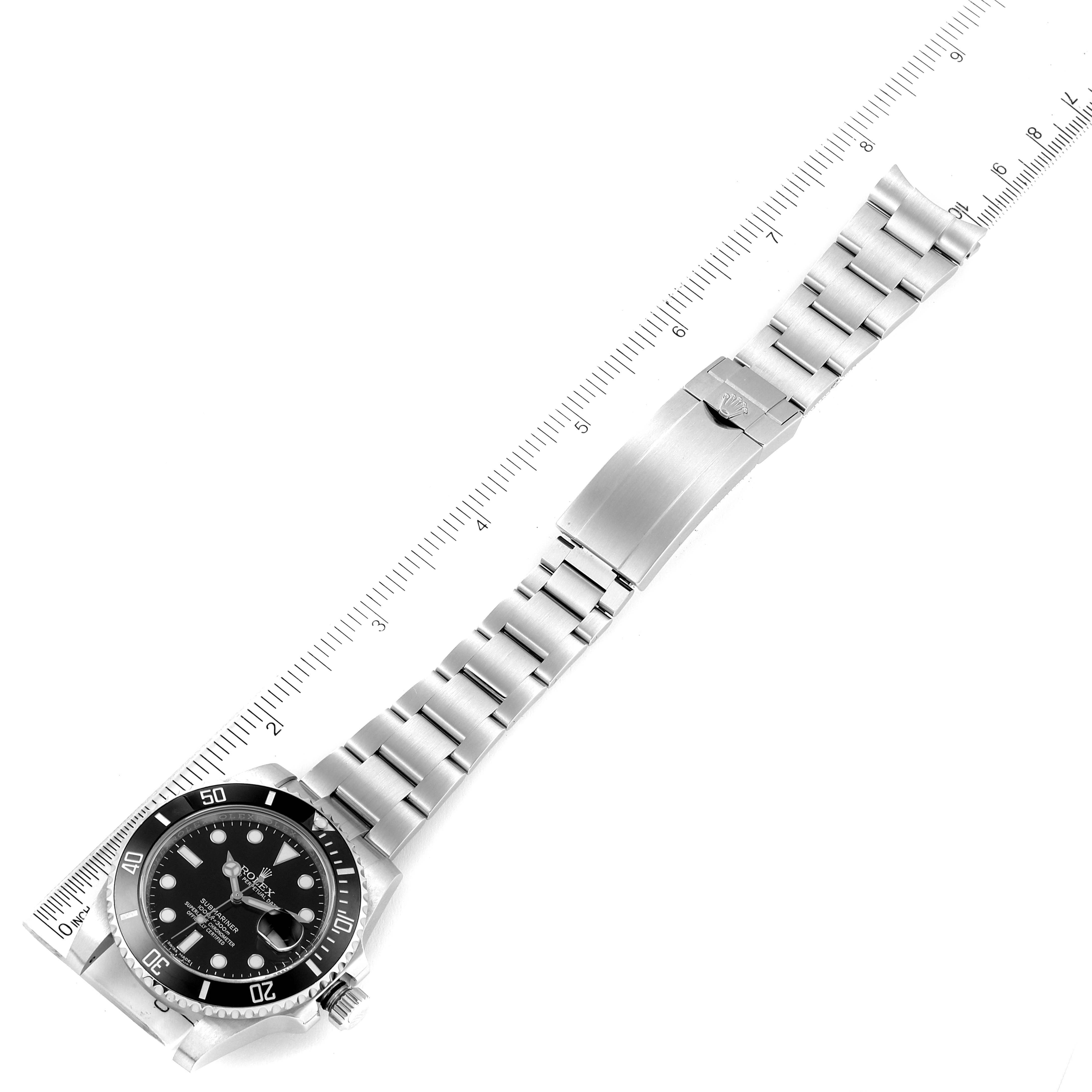 The image shows a top-down view of a Rolex Submariner 116610 Men
s Stainless Steel Black Dial 116610 Men
s Stainless Steel Black Dial watch with the stainless steel bracelet fully extended, alongside a ruler.