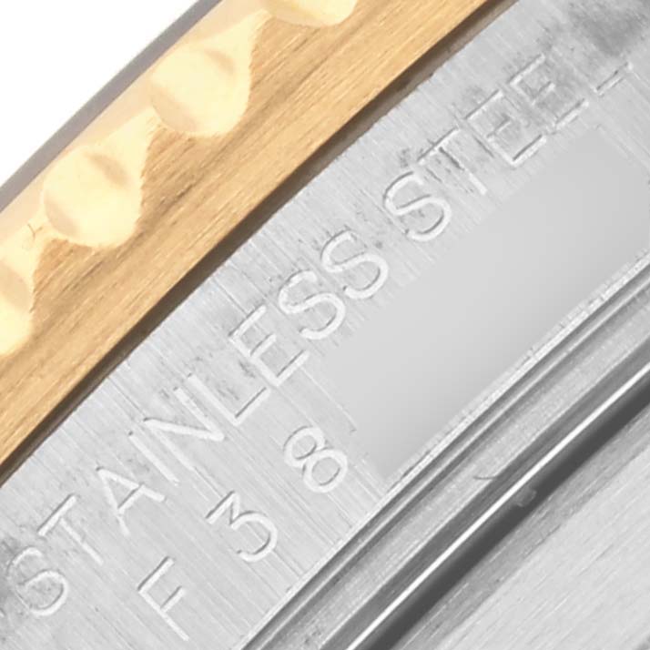 The image shows a close-up of a Rolex Submariner 16613 Men's Steel and Gold (two tone) Blue Dial 16613 Men's Steel and Gold (two tone) Blue Dial's stainless steel case back and part of the gold bezel edge.