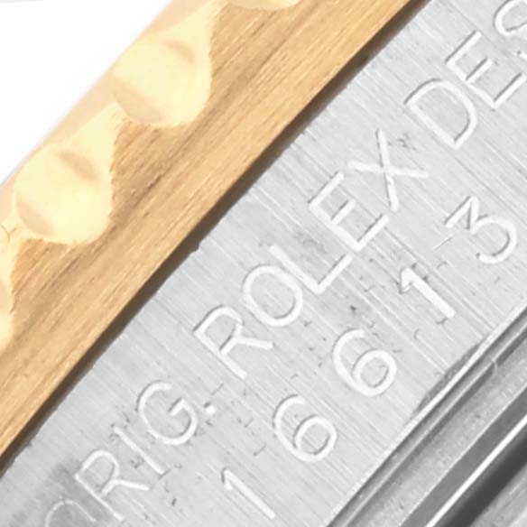 The image shows a close-up of the side of a Rolex Submariner 16613 Men's Steel and Gold (two tone) Blue Dial 16613 Men's Steel and Gold (two tone) Blue Dial, highlighting the engraved serial information and gold bezel.
