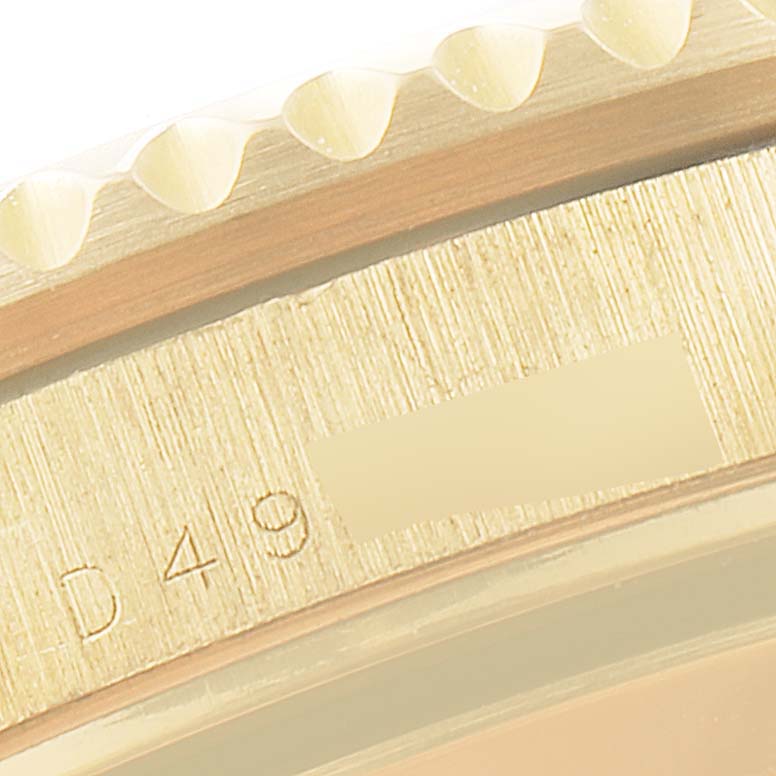 The close-up angle of this Rolex Submariner 16618 Men
s Yellow Gold Blue Dial 16618 Men
s Yellow Gold Blue Dial shows the edge of the bezel and part of the case with engraved markings.