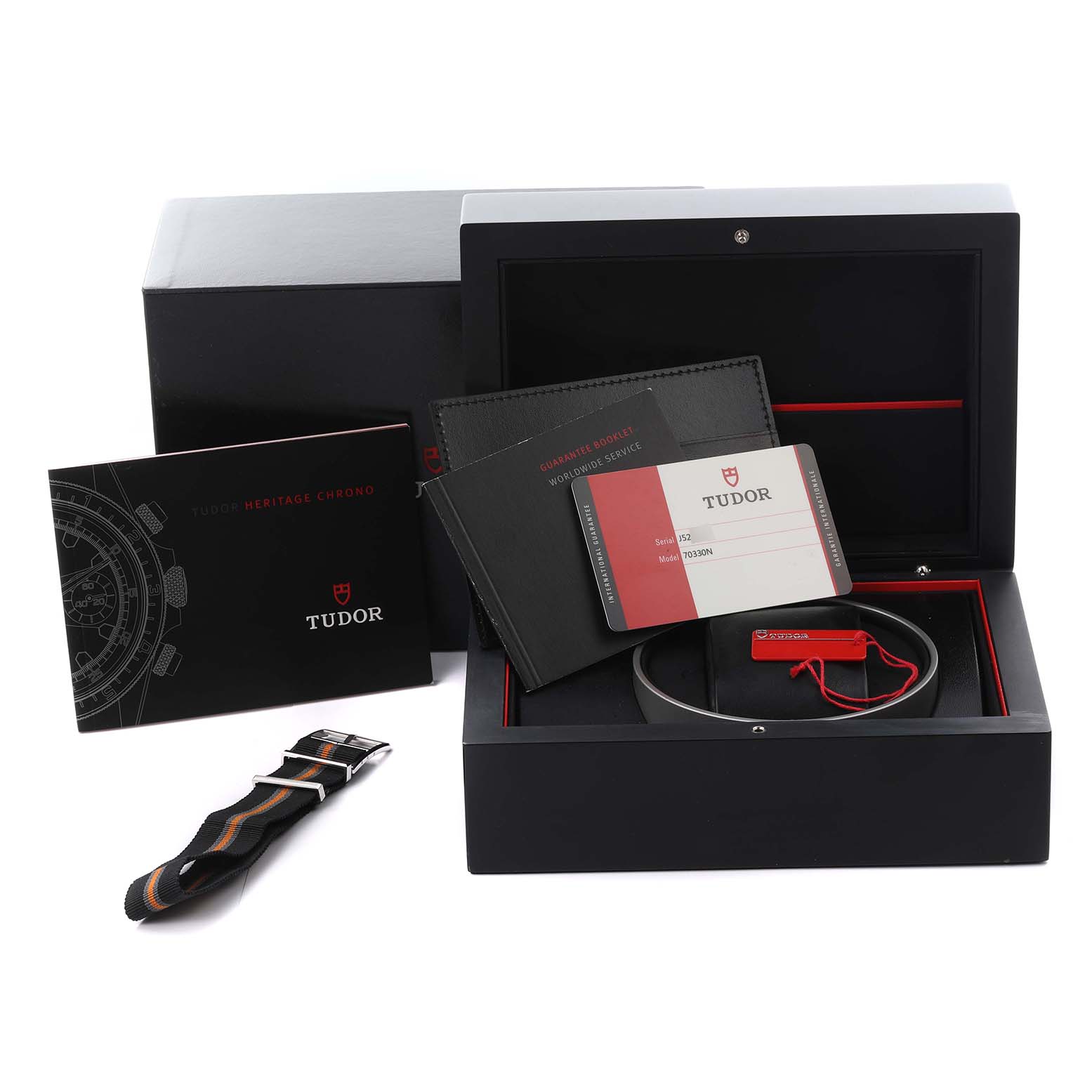 The image shows the Tudor Heritage Chrono 70330N-65740 Men's Stainless Steel Grey Dial 70330N-65740 Men's Stainless Steel Grey Dial packaging including a box, manuals, warranty card, and a strap, viewed from the top.