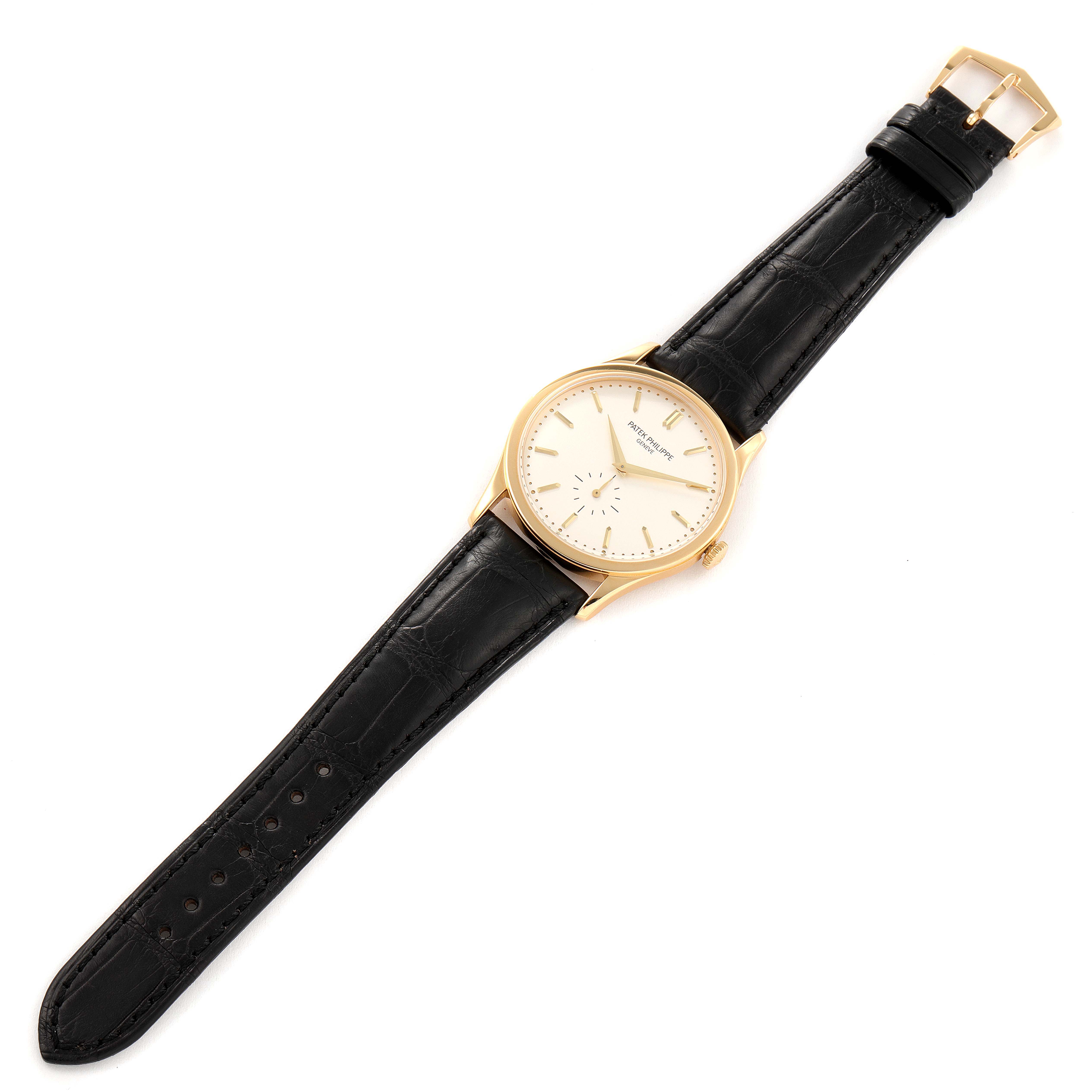 The image shows a top-down view of a Calatrava model by Patek Philippe, including the black leather strap and gold case.