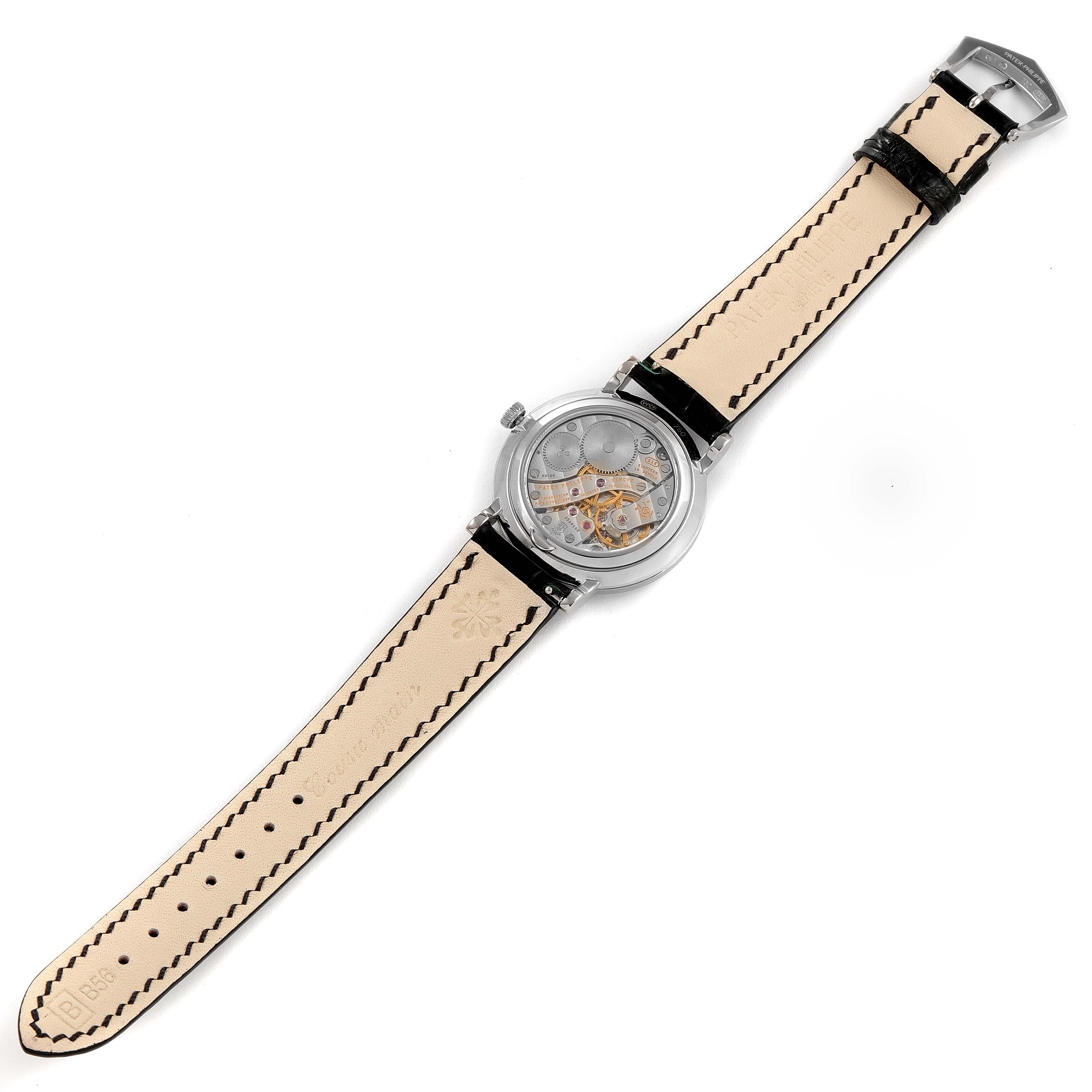 The image shows the back view of a Patek Philippe Calatrava 7119G Men's White Gold Silver Dial 7119G Men's White Gold Silver Dial watch, displaying its movement and leather strap.