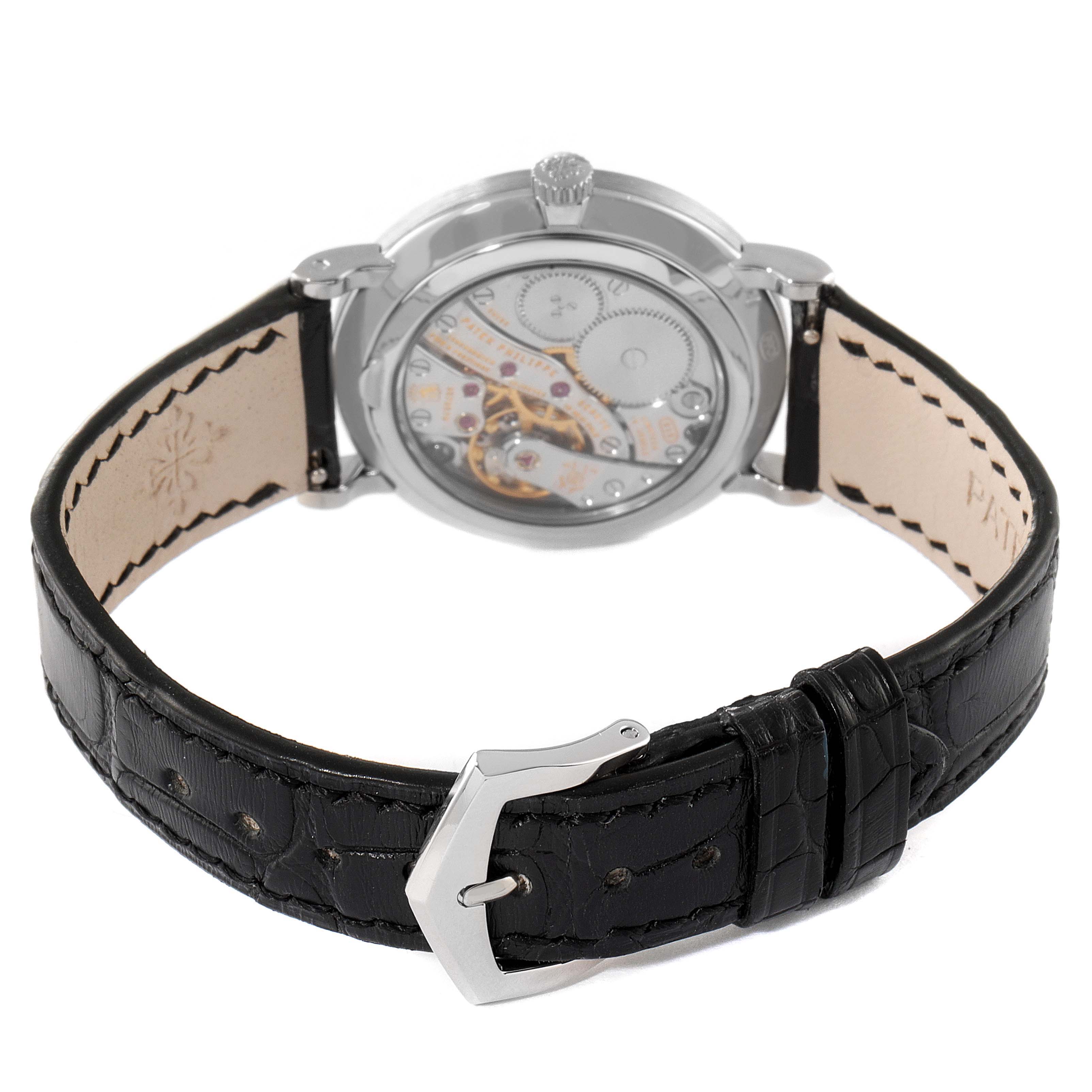 The image shows the back view of a Patek Philippe Calatrava 7119G Women's White Gold White Dial 7119G Women's White Gold White Dial watch, highlighting its movement and black leather strap.