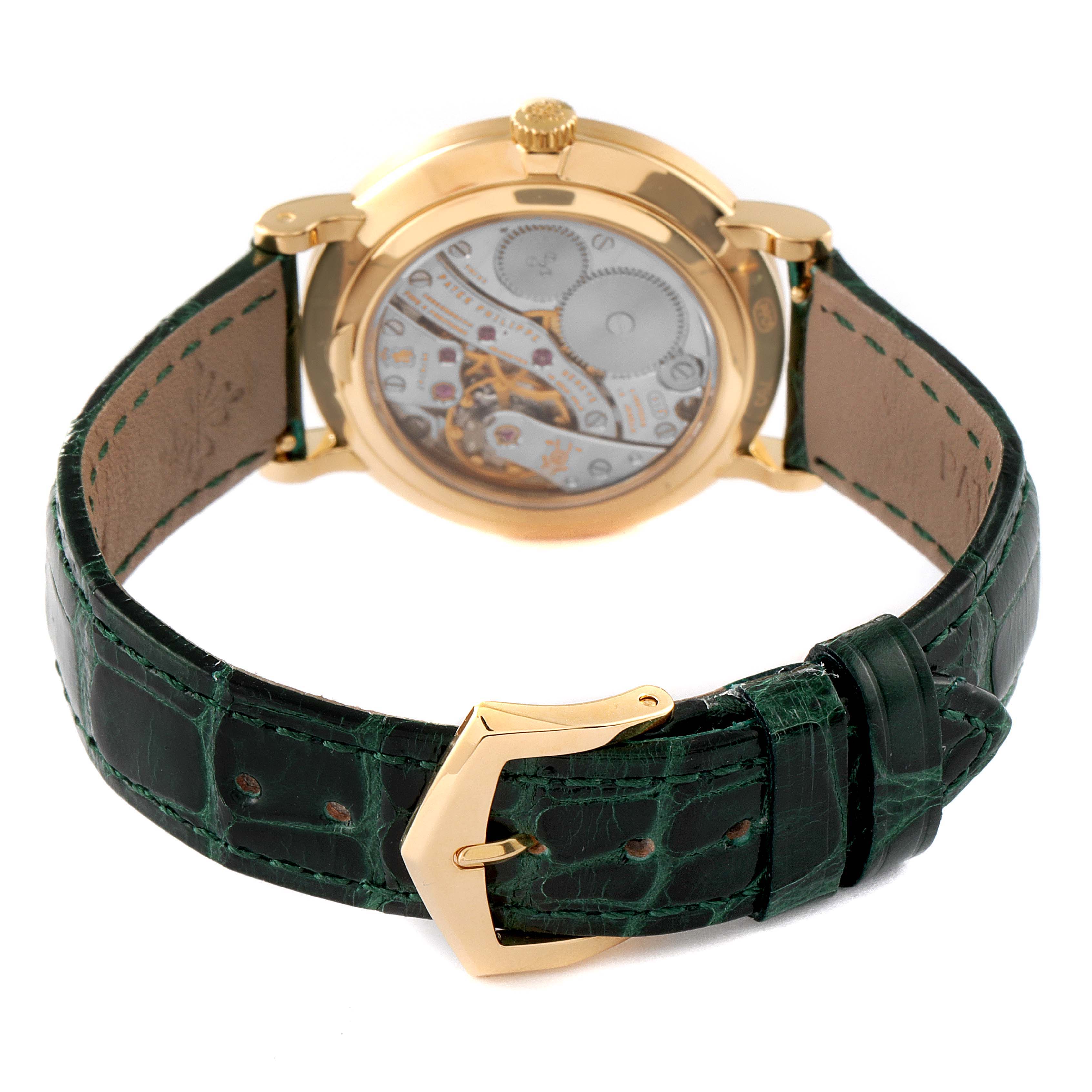 This image shows a Patek Philippe Calatrava 7119J Women's Yellow Gold White Dial 7119J Women's Yellow Gold White Dial watch from the rear, highlighting the movement and green leather strap with a gold buckle.