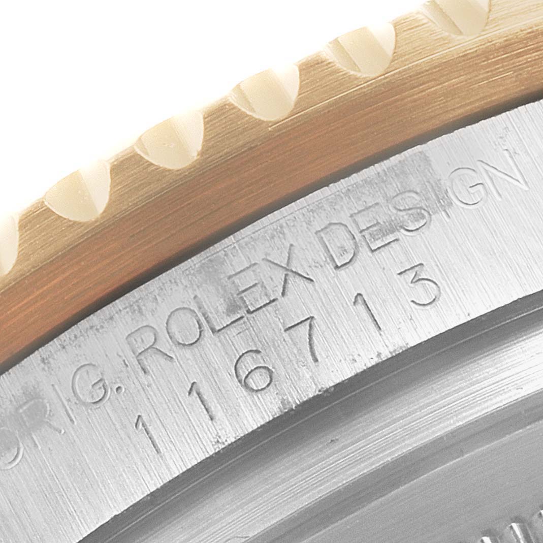 This image shows a close-up of the case side engraving and bezel of a Rolex GMT-Master 116713 Men's Steel and Gold (two tone) Black Dial 116713 Men's Steel and Gold (two tone) Black Dial watch.