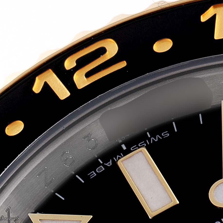 This image shows a close-up of the 12 o'clock position and part of the bezel on a Rolex GMT-Master 116713 Men's Steel and Gold (two tone) Black Dial 116713 Men's Steel and Gold (two tone) Black Dial watch.