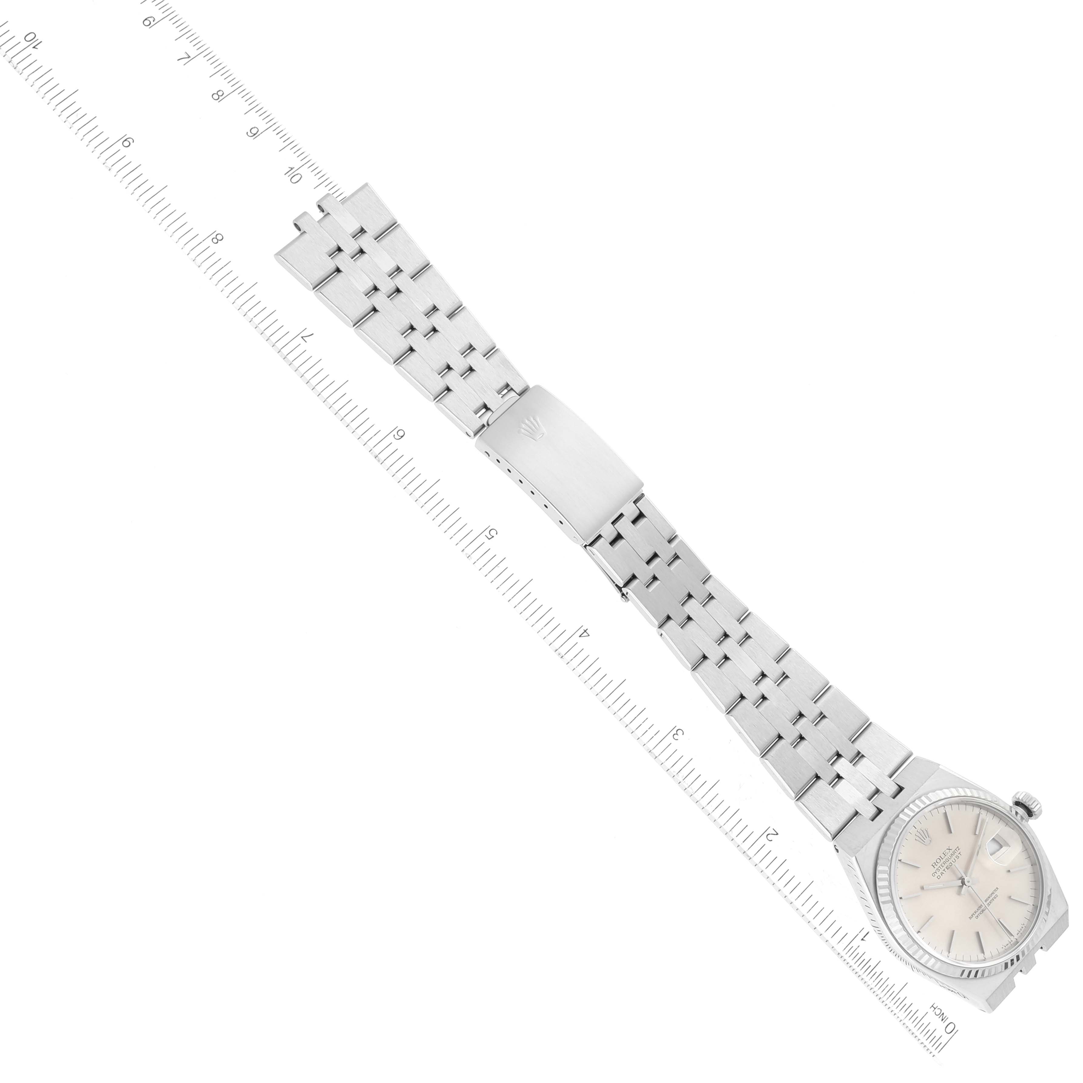 This image shows a top-down view of a Rolex Oysterquartz 17014 Men
s Stainless Steel Silver Dial 17014 Men
s Stainless Steel Silver Dial watch, including its face, bracelet, and clasp with a ruler for scale.