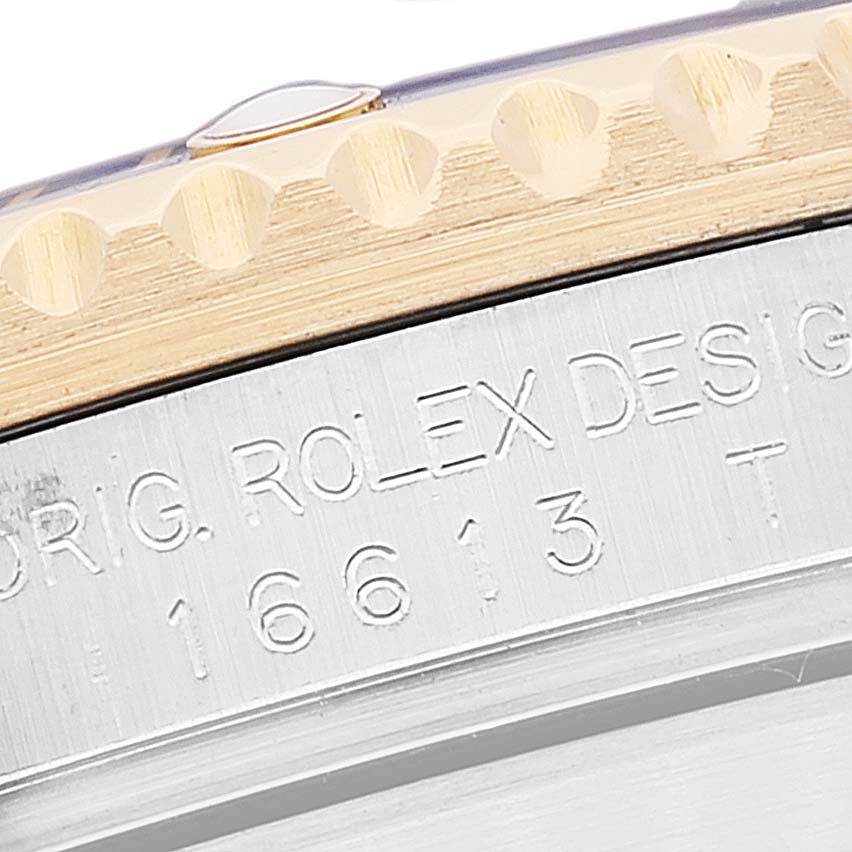 The image shows a macro view of the Rolex Submariner 16613 Men's Steel and Gold (two tone) Blue Dial 16613 Men's Steel and Gold (two tone) Blue Dial's bezel and engraved case side.