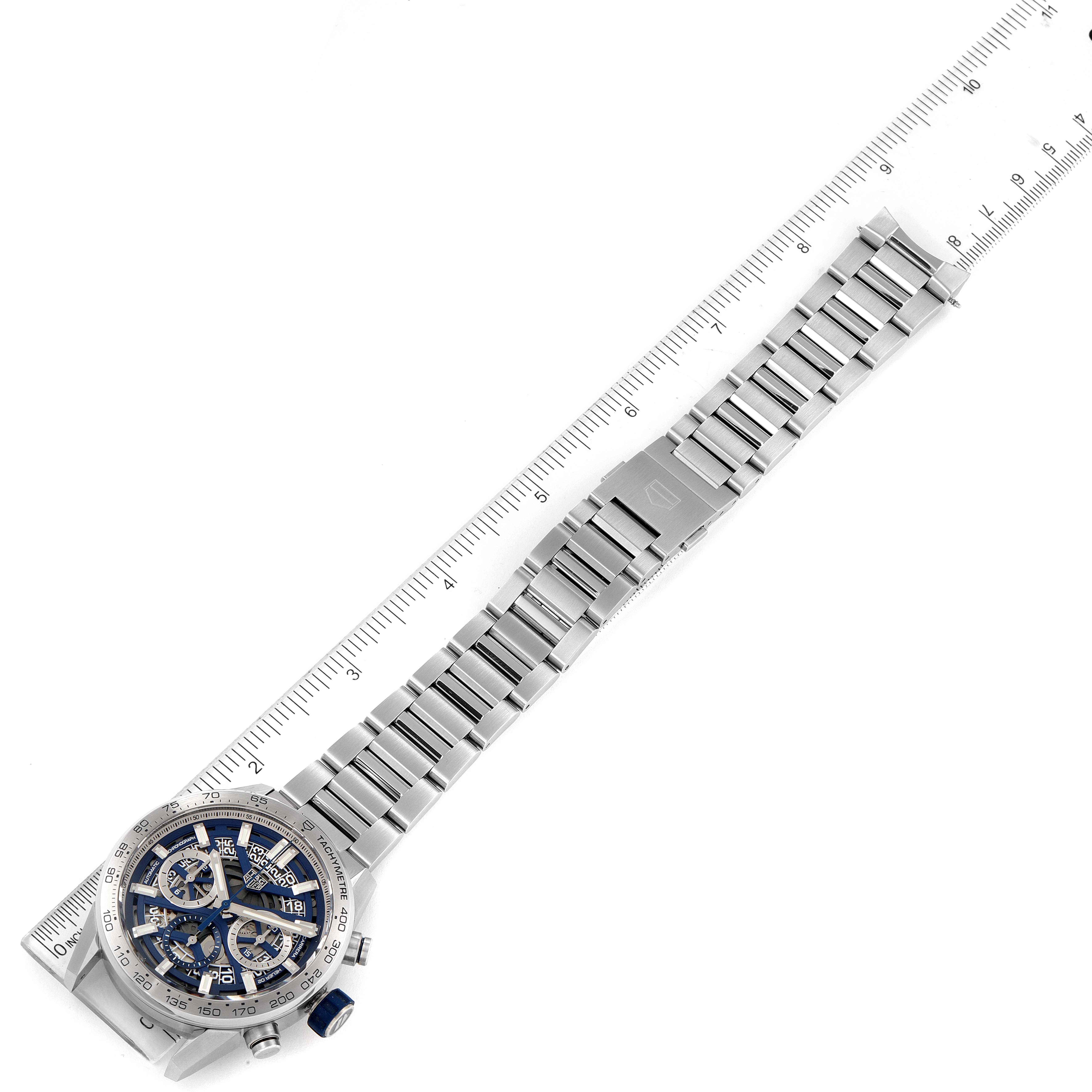 The image shows a top-down view of a Tag Heuer Carrera watch with its stainless steel bracelet alongside a measurement ruler.