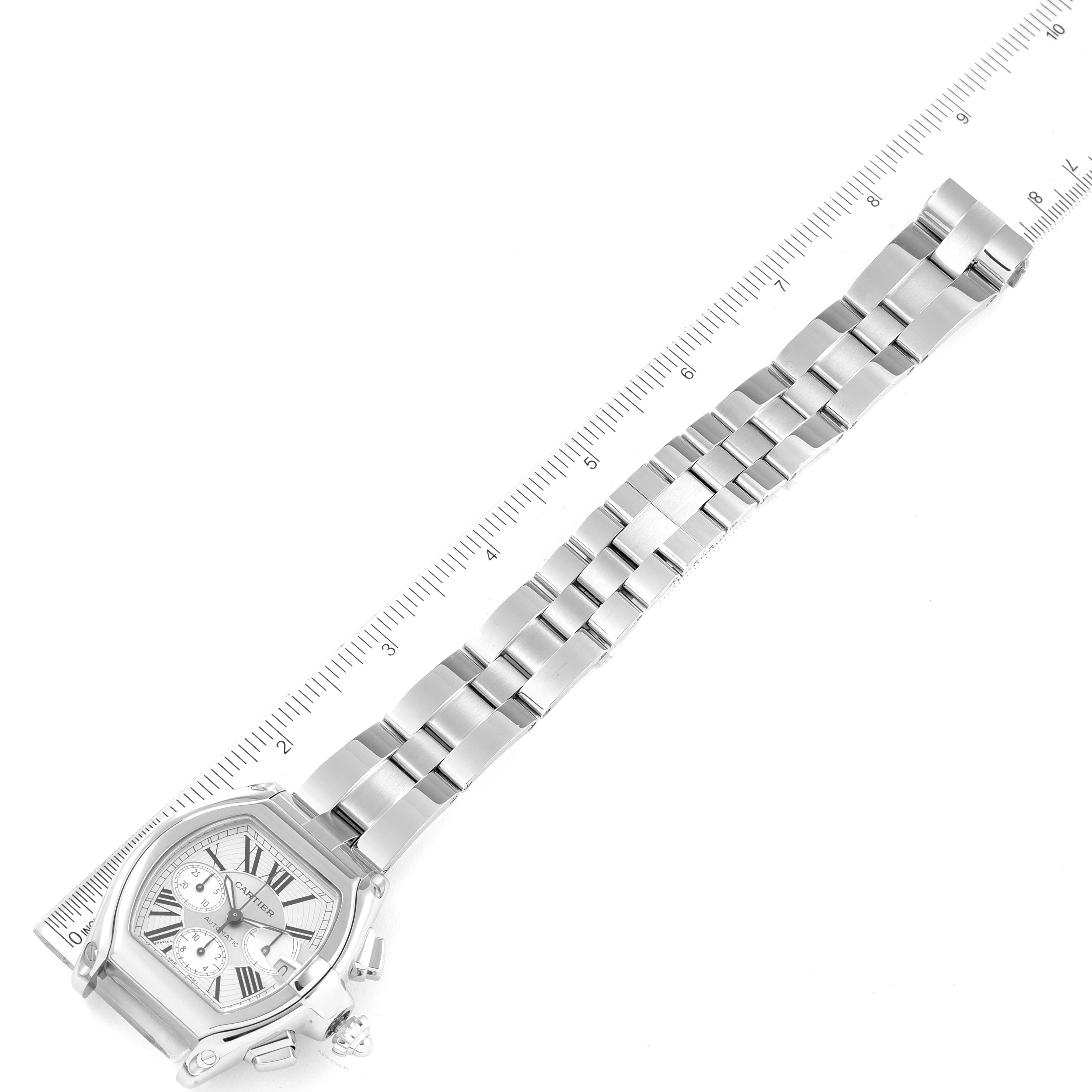 The image shows a Cartier Roadster W62019X6 Men
s Stainless Steel Silver Dial W62019X6 Men
s Stainless Steel Silver Dial watch laid flat with its full strap extended next to a ruler.