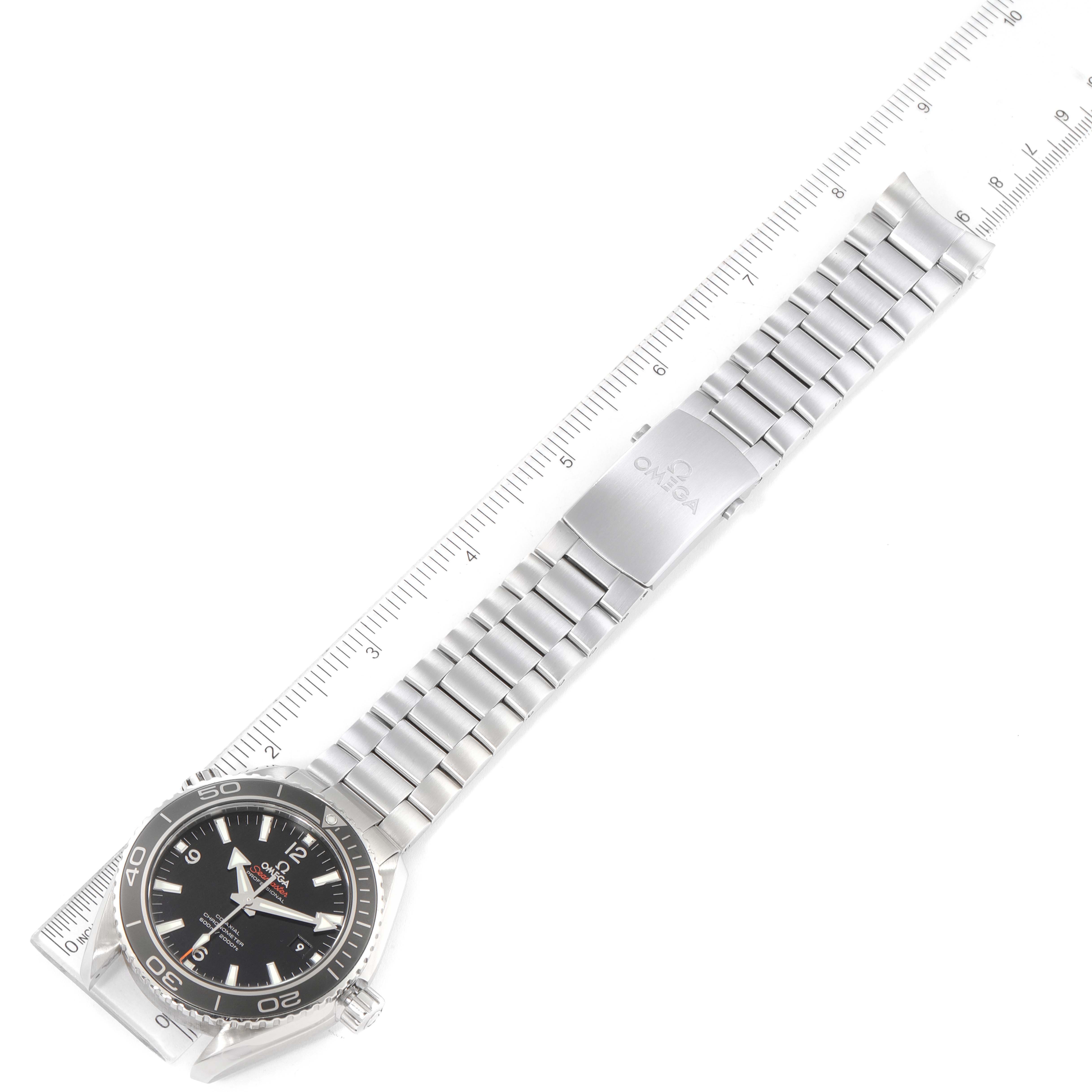 The Omega Planet Ocean 232.30.46.21.01.001 Men's Stainless Steel Black Dial 232.30.46.21.01.001 Men's Stainless Steel Black Dial watch is shown from an overhead angle, displaying its face, bezel, and metal bracelet with a ruler for scale.