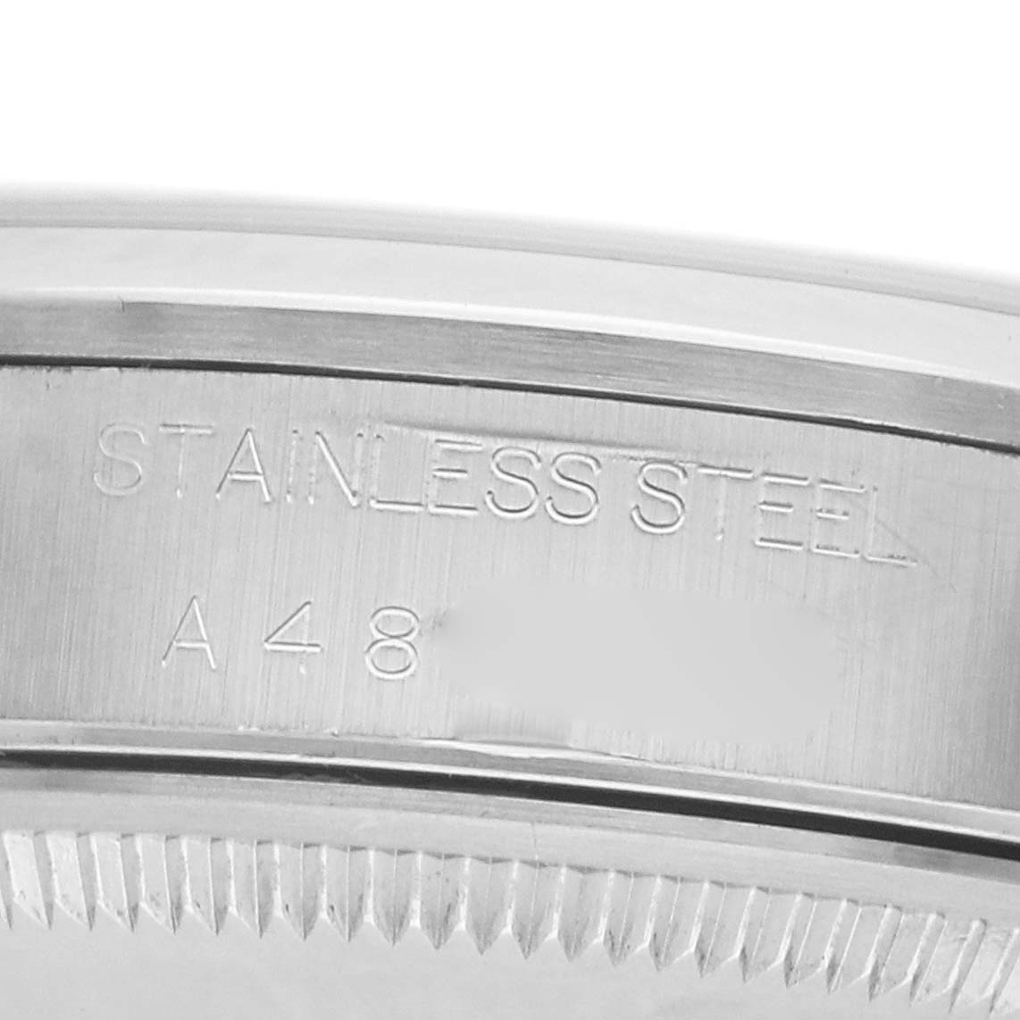The image shows a close-up of the engraved bezel edge of a Rolex Date 15200 Men's Stainless Steel Silver Dial model, highlighting "Stainless Steel."