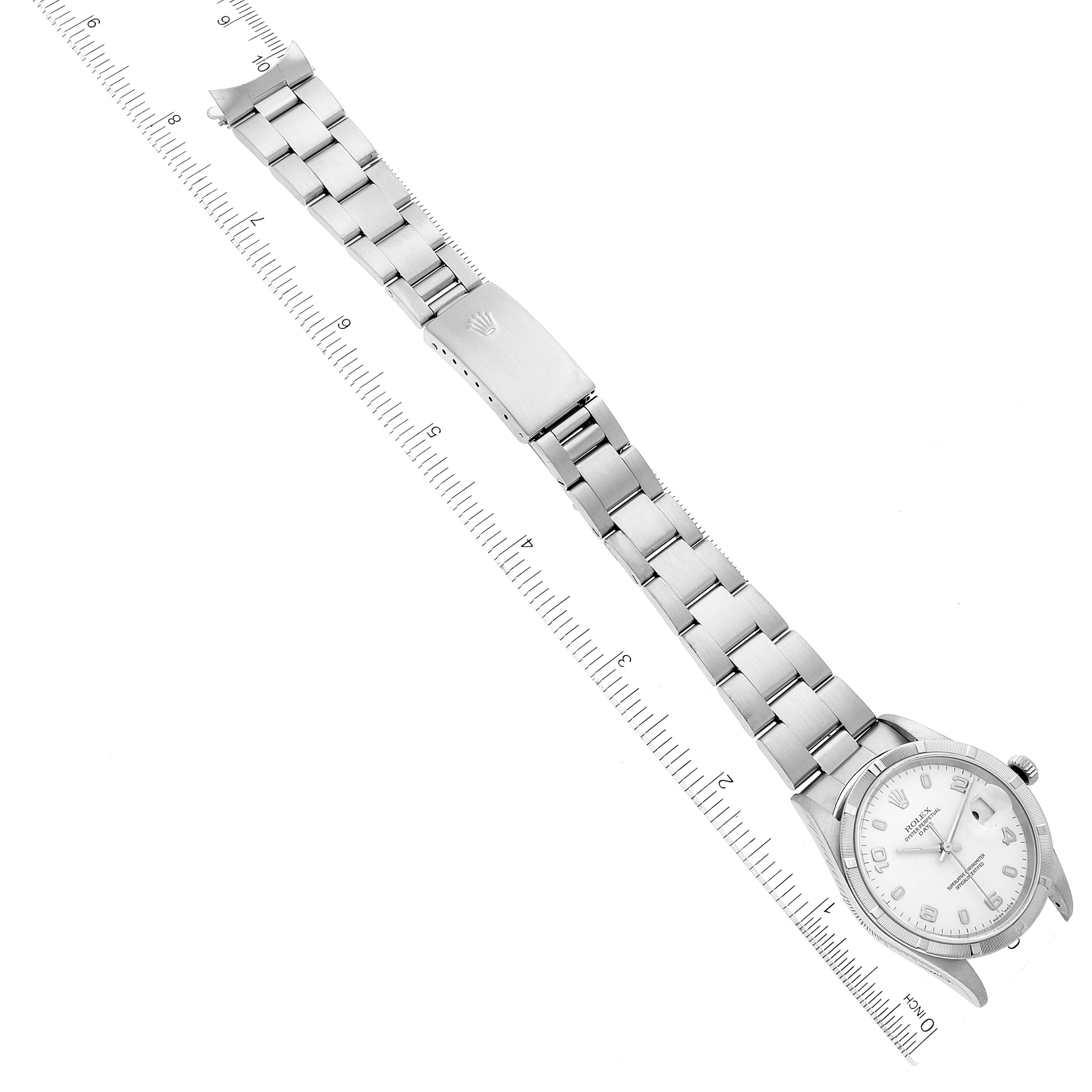 This top-down image shows the Rolex Date 15210 Men's Stainless Steel White Dial 15210 Men's Stainless Steel White Dial model watch and its bracelet laid alongside a ruler for scale.