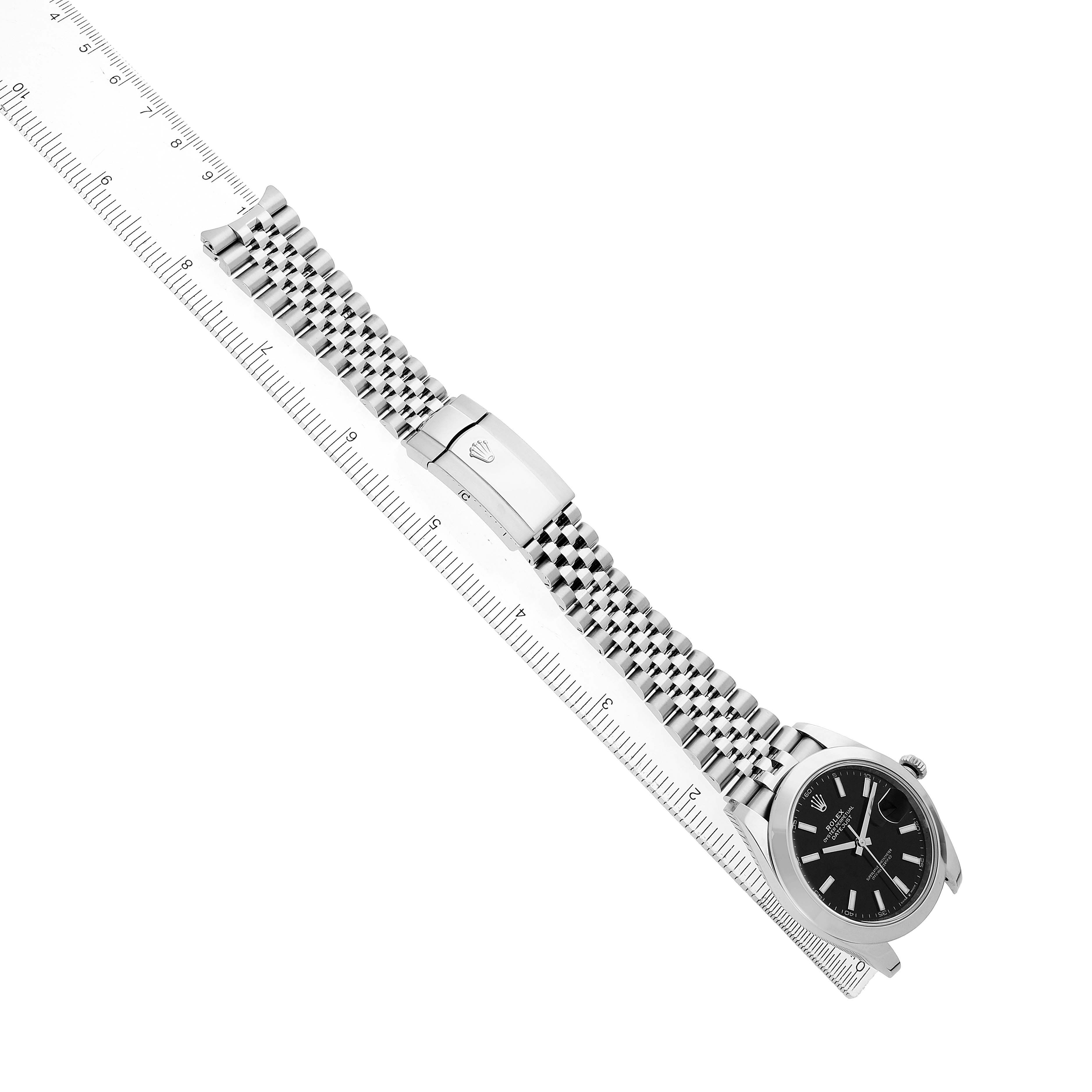 The Rolex Datejust 41 126300 Men's Stainless Steel Black Dial watch is shown at an angle displaying the bezel, dial, bracelet, and clasp, with a ruler for scale.