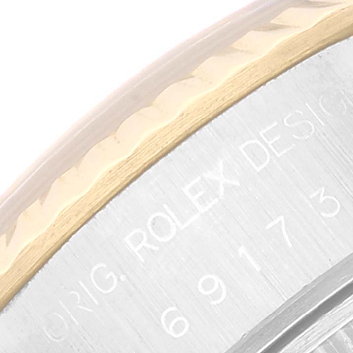 This close-up angle of a Rolex Datejust 69173 Women's Steel and Gold (two tone) Champagne Dial 69173 Women's Steel and Gold (two tone) Champagne Dial watch shows part of the fluted bezel and engraved text on the side of the watch case.
