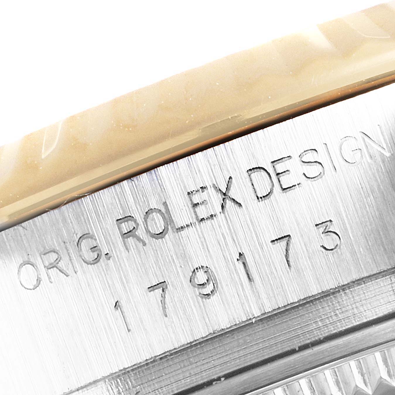 This close-up image shows the engraved serial number and "ORIG. ROLEX DESIGN" text on the case of a Rolex Datejust 179173 Women
s Steel and Gold (two tone) Champagne Dial 179173 Women
s Steel and Gold (two tone) Champagne Dial watch.
