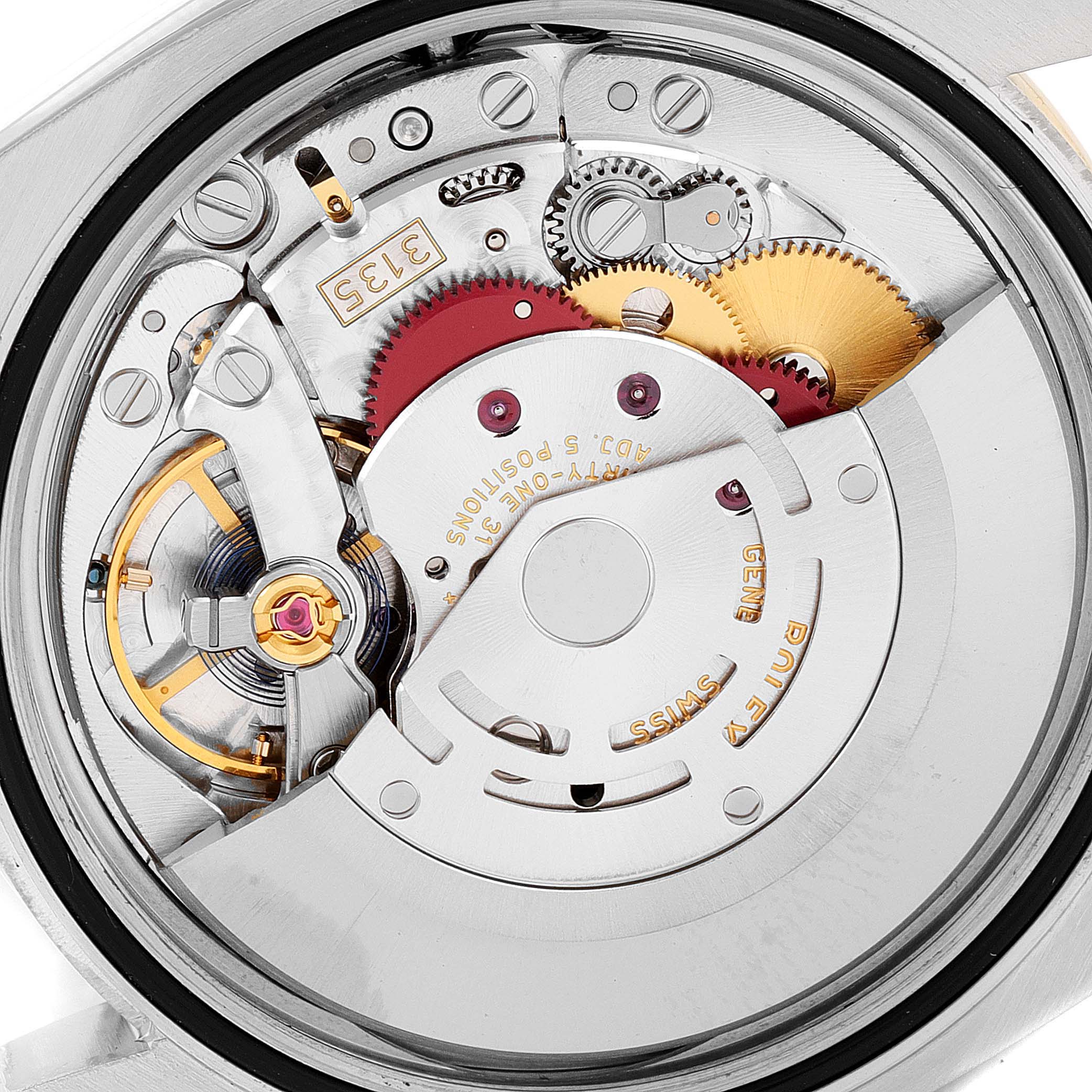 The image shows the internal mechanism of a Rolex Datejust 116243 Men's Steel and Gold (two tone) White Dial 116243 Men's Steel and Gold (two tone) White Dial watch from a close-up angle, highlighting the gears and movement components.