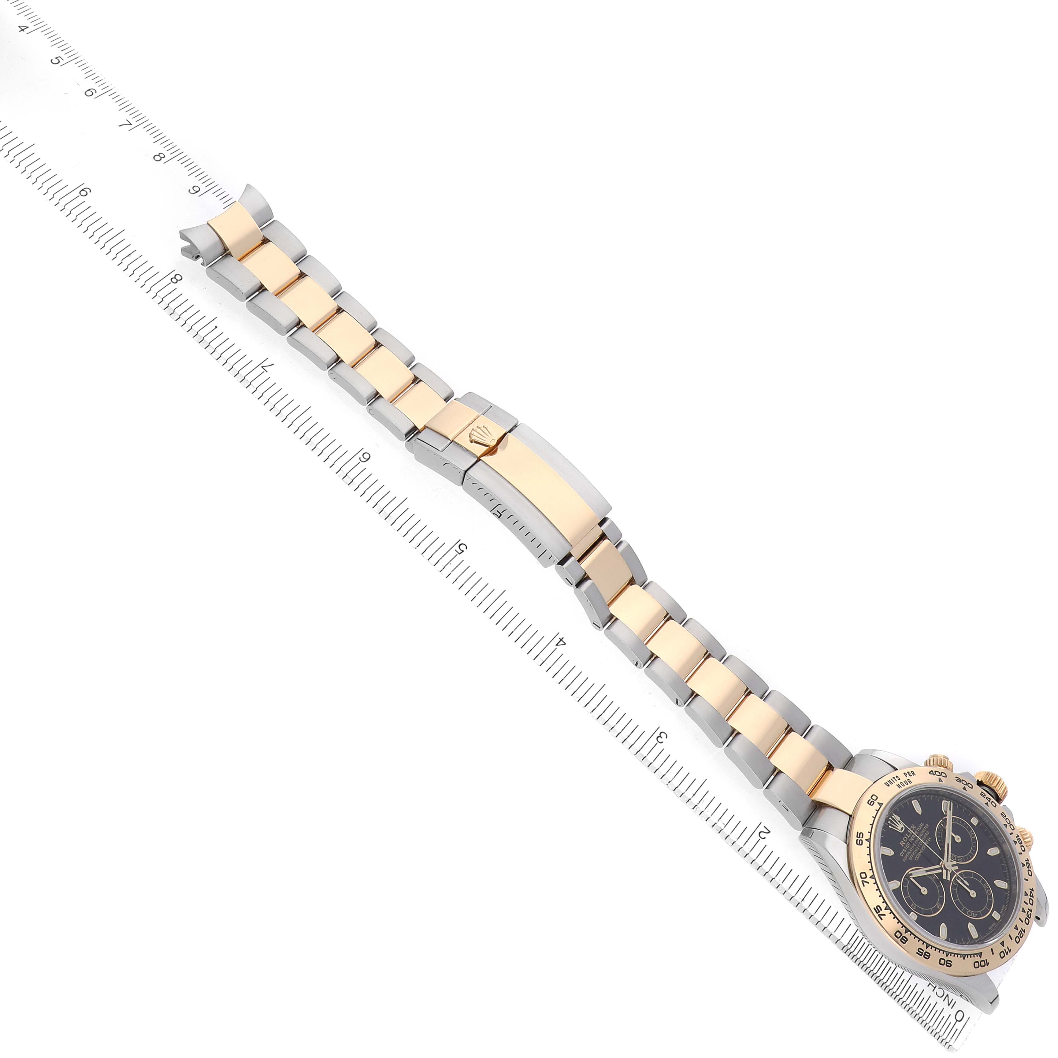 The Rolex Daytona 116503 Men's Steel and Gold (two tone) Black Dial watch is shown at an angle with a full view of the bracelet and clasp beside a ruler.