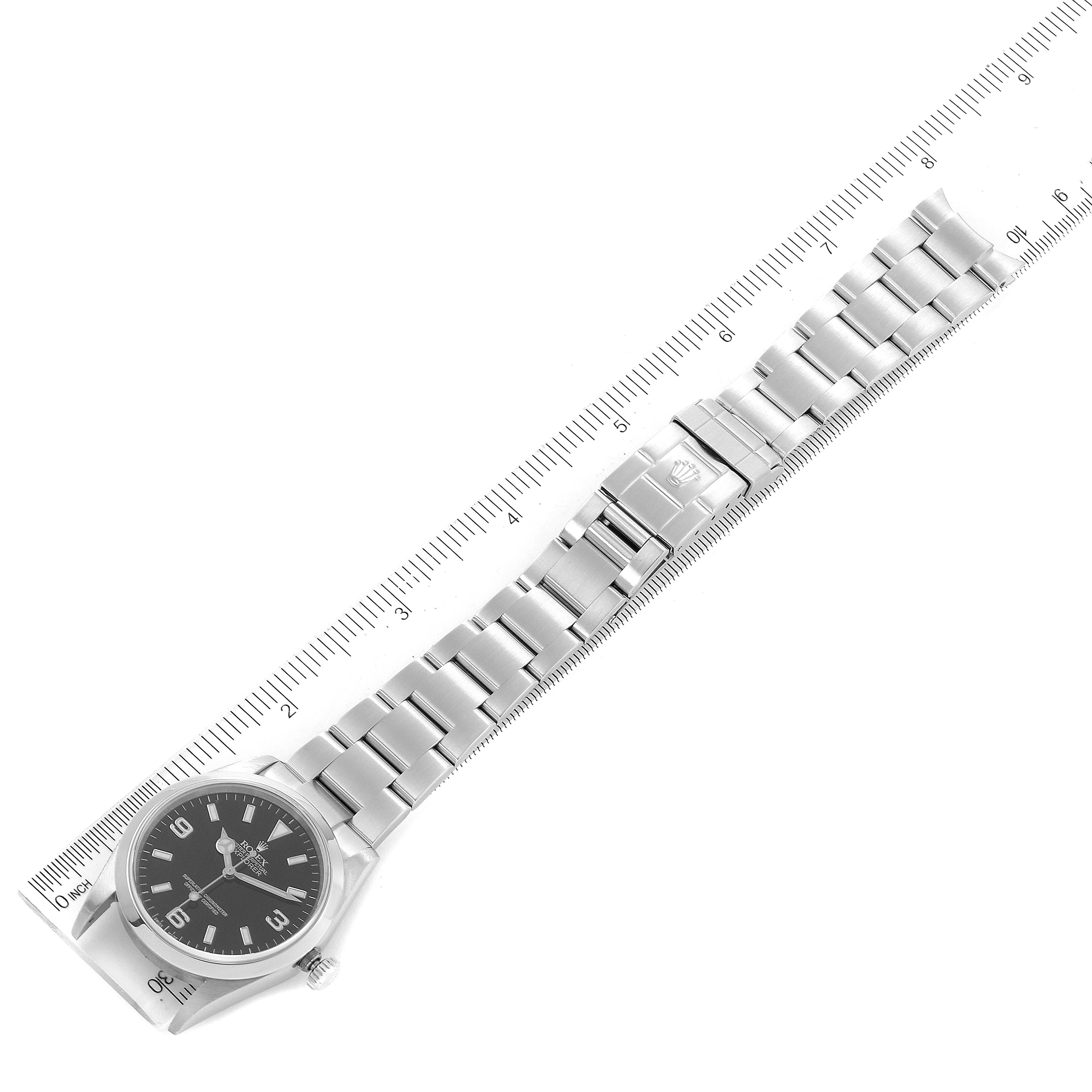 The image shows a Rolex Explorer 114270 Men
s Stainless Steel Black Dial 114270 Men
s Stainless Steel Black Dial watch from a top-down angle, displaying the entire watch band against a measuring ruler.
