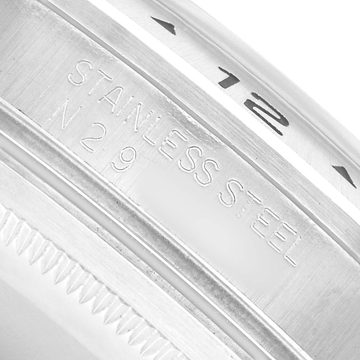 The image shows a close-up of the bezel and edge, featuring engravings like "STAINLESS STEEL" on a Rolex Explorer 16570 Men's Stainless Steel Black Dial watch.
