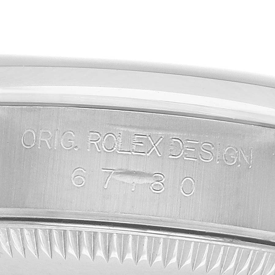 The image shows the side view of the bezel and part of the case of a Rolex Oyster Perpetual 67180 Women's Stainless Steel Blue Dial, highlighting the engraved model number.