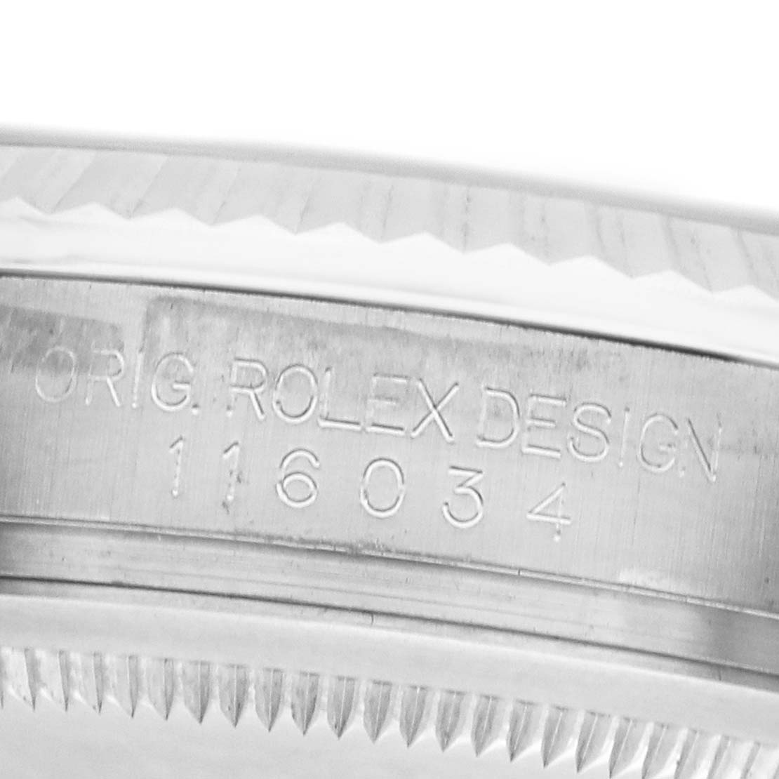 The image shows a close-up of the engraved side of the Rolex Oyster Perpetual 116034 Men's Stainless Steel Silver Dial's case, displaying its design and model number.