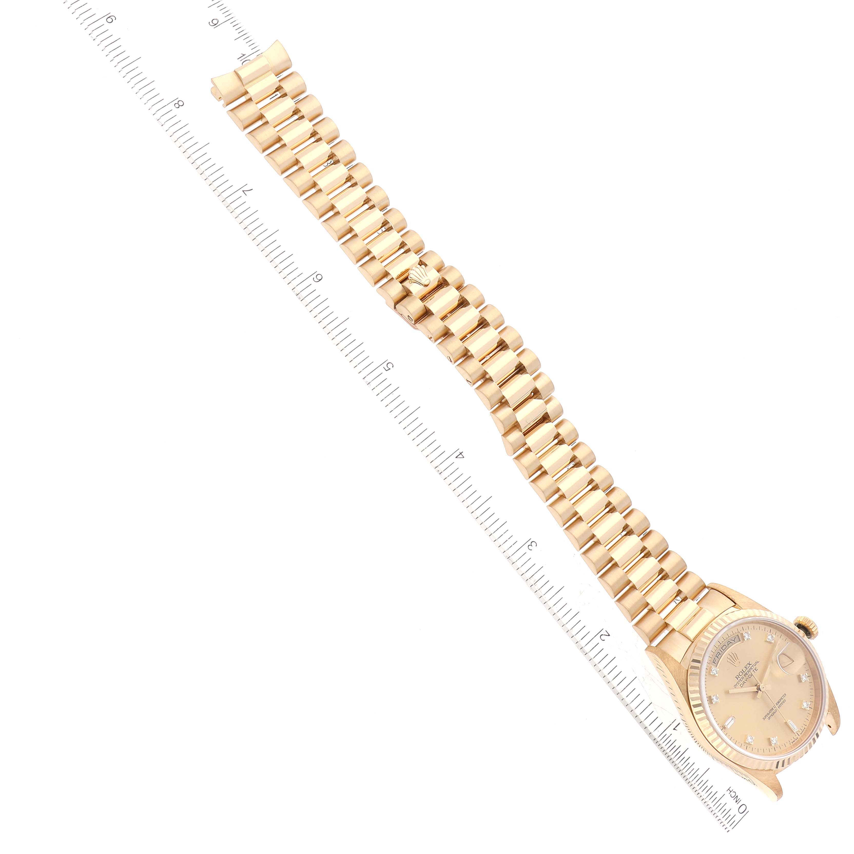 This image shows a Rolex President 18238 Men
s Yellow Gold Champagne Dial 18238 Men
s Yellow Gold Champagne Dial watch laid flat with the band extended along a ruler for measurement.